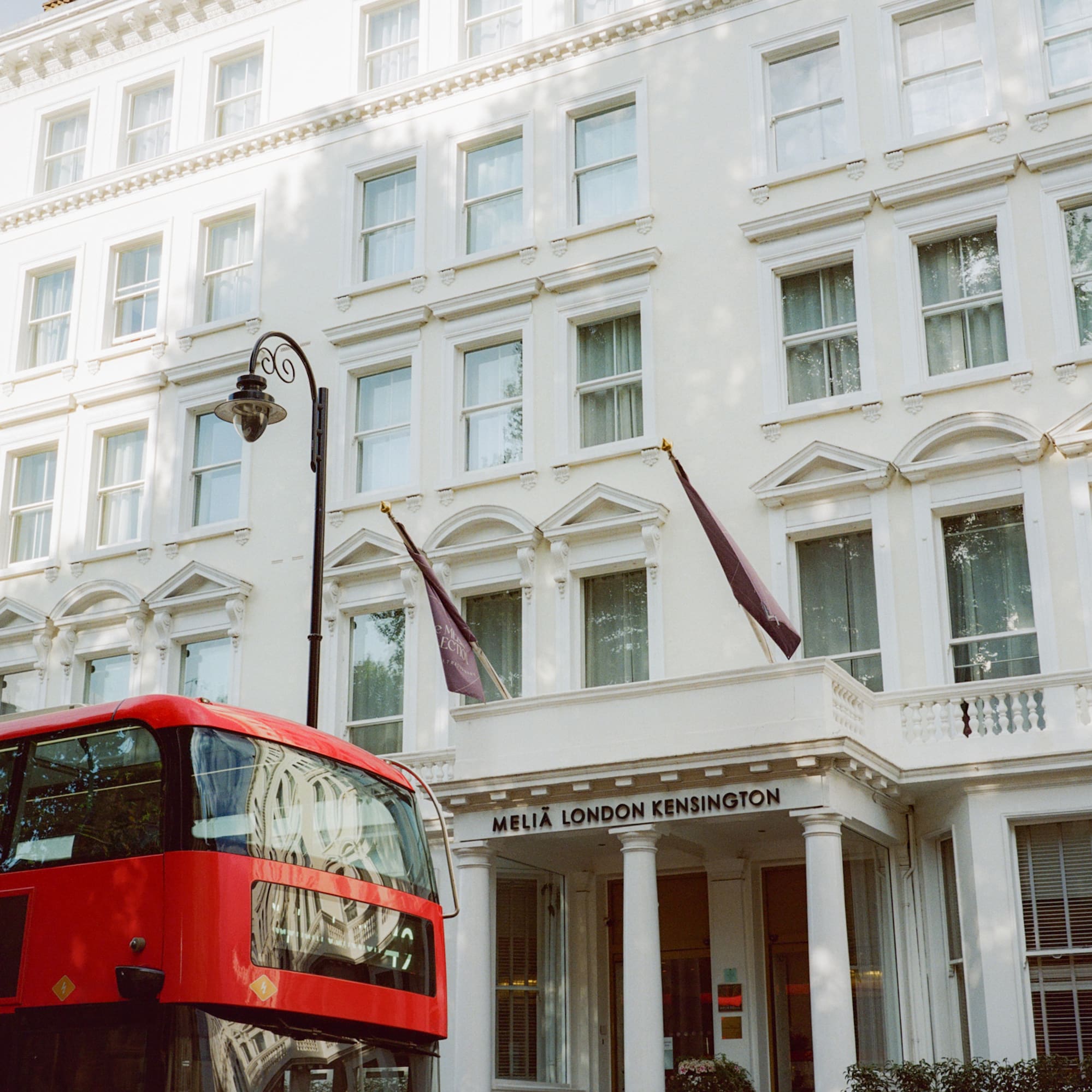 Red double-decker bus in front of Melia London Kensington hotel.