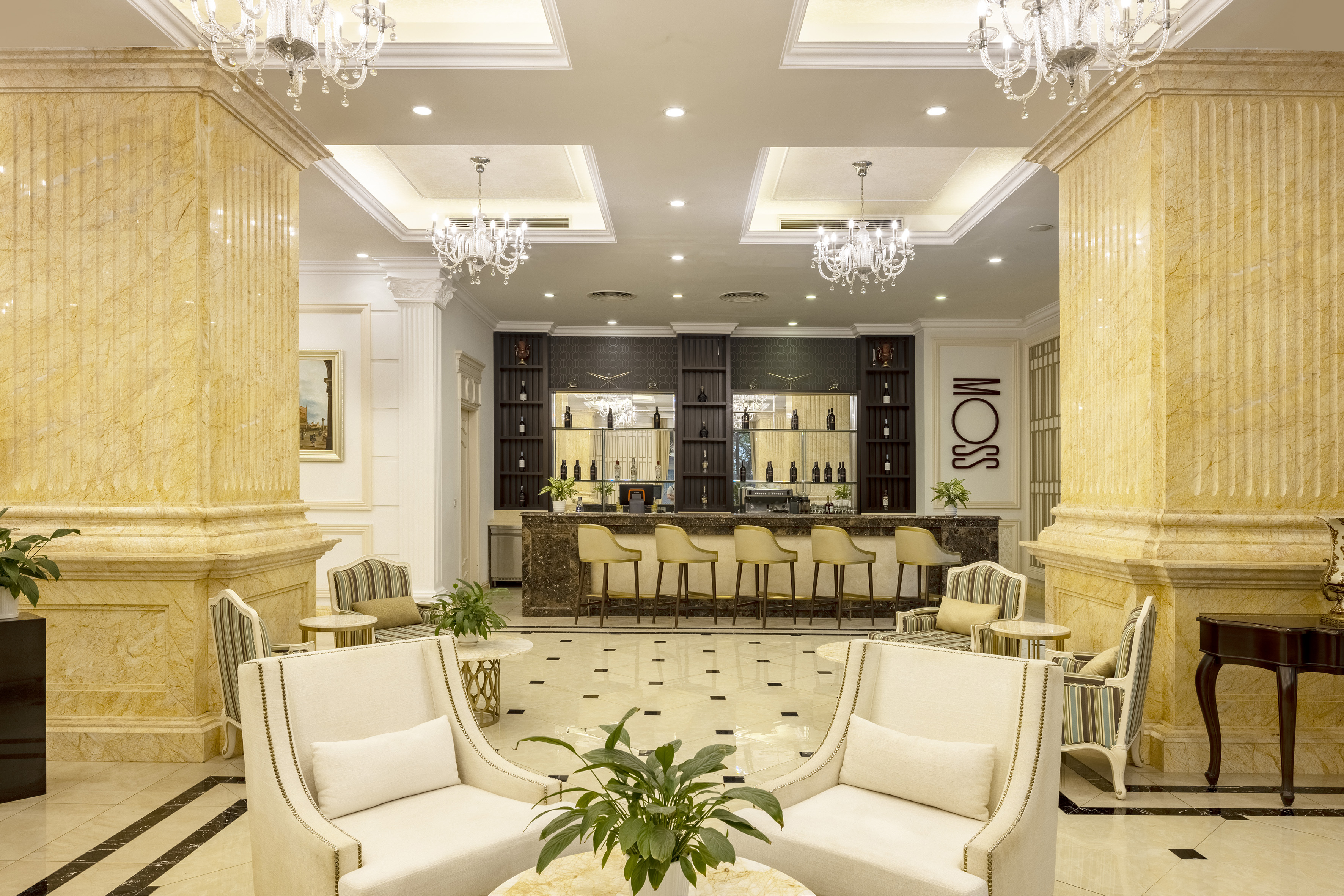 MOSS hotel bar lounge with marble columns, chandeliers, and elegant seating.
