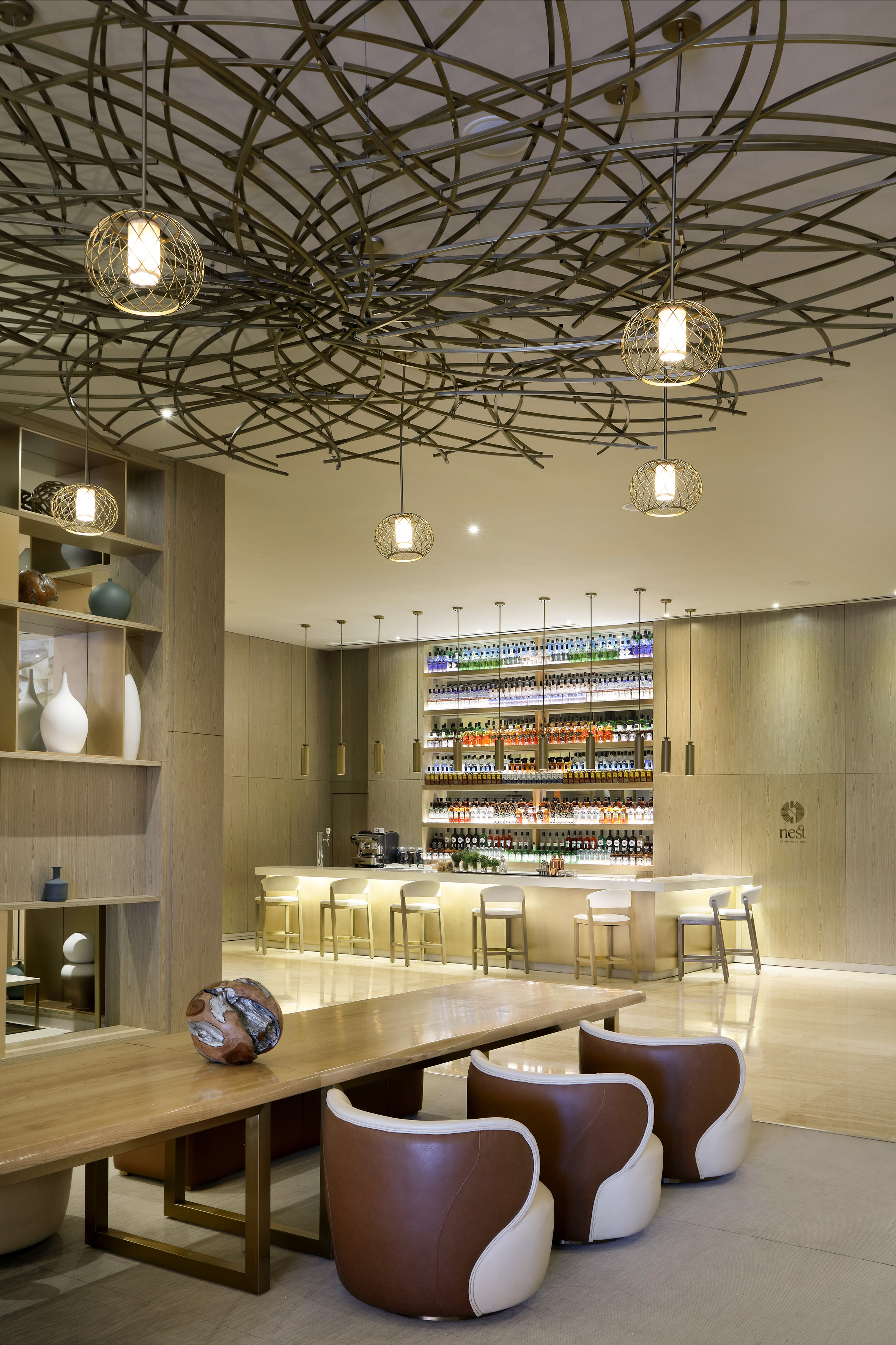 Nest Wine Boutique bar with bottles, modern geometric ceiling, and lounge seating.