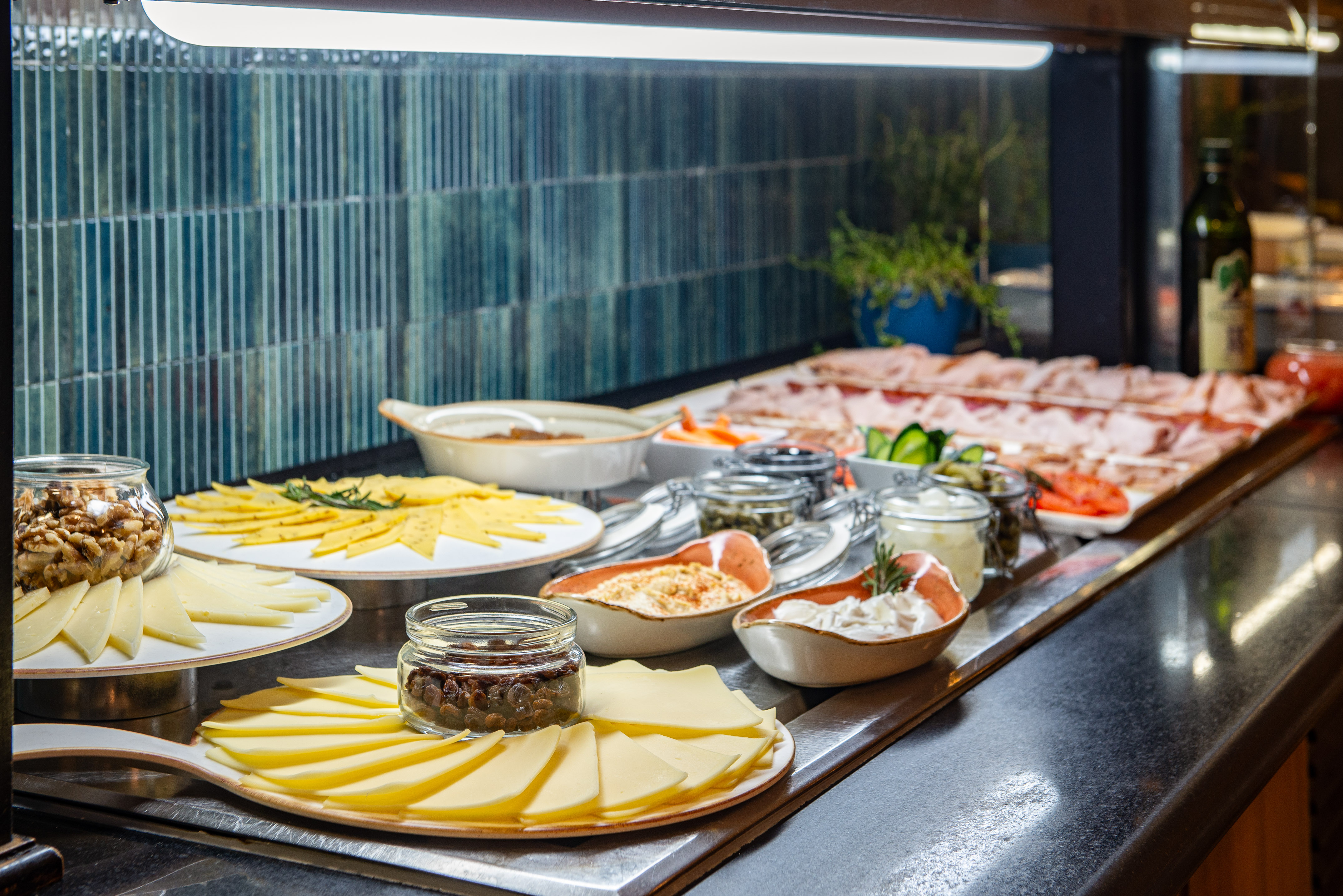 Hotel buffet breakfast spread with cheese, cold cuts, nuts, and savory dips.