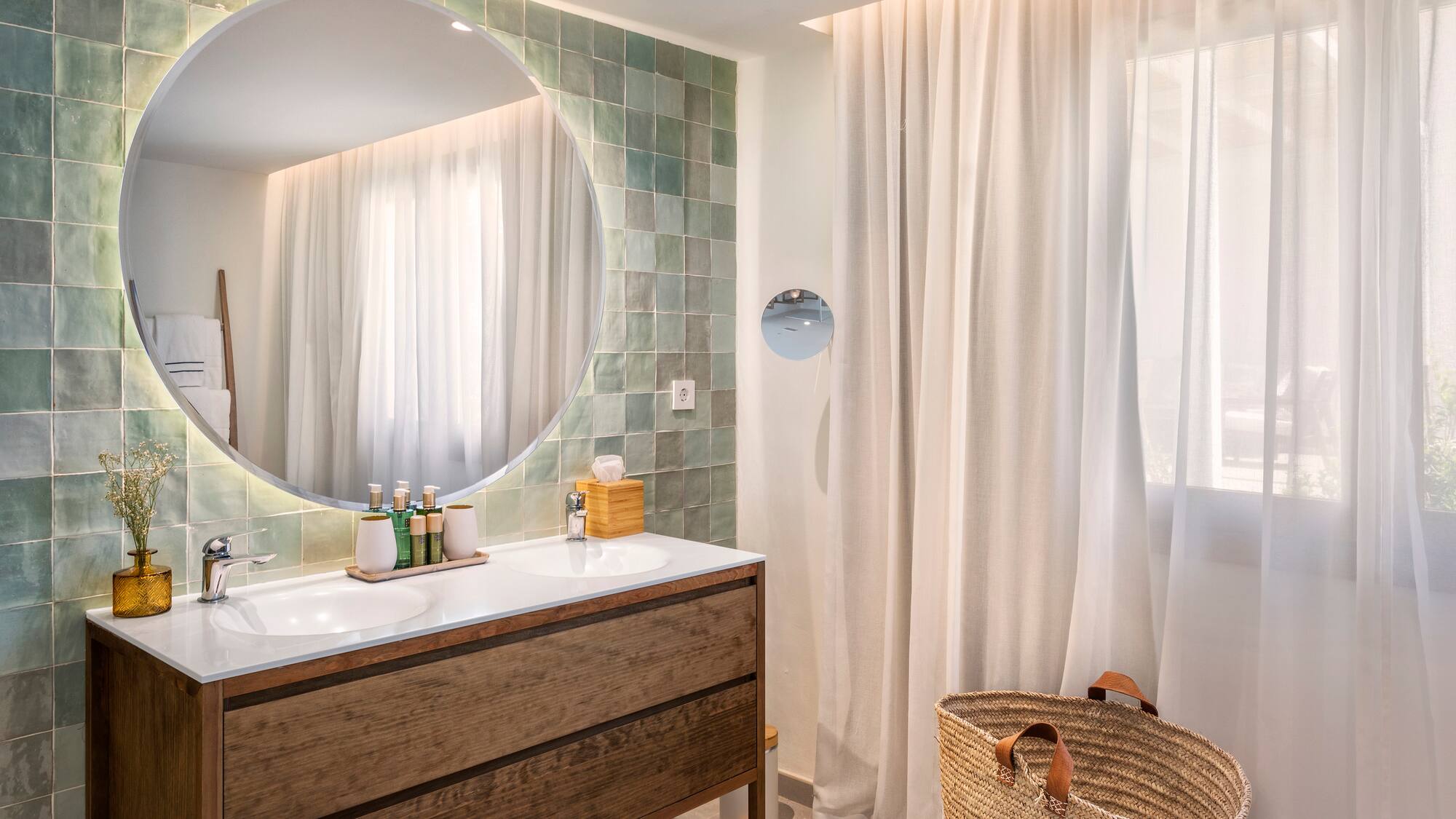 a bathroom with a round mirror and a basket