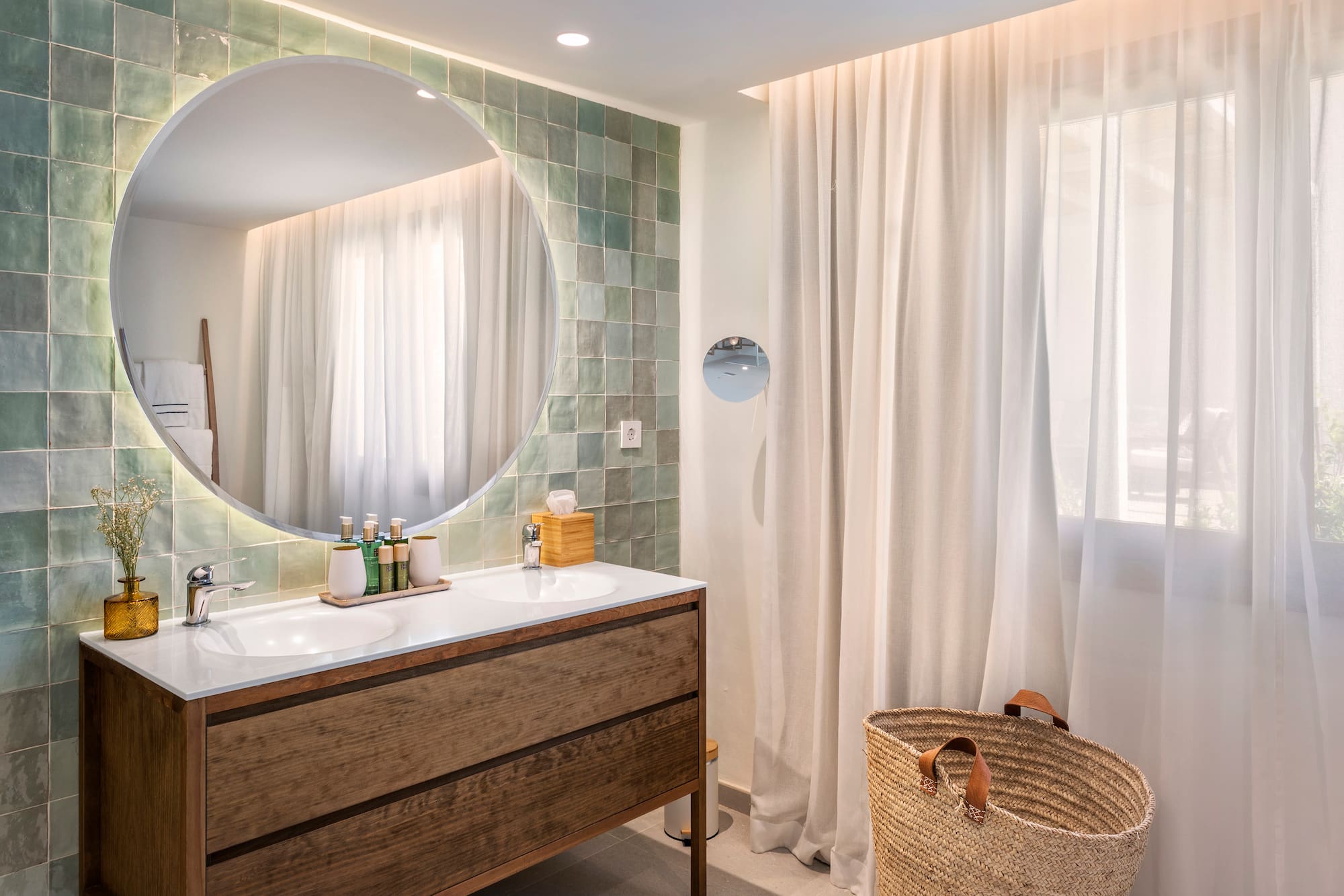 a bathroom with a round mirror and a basket