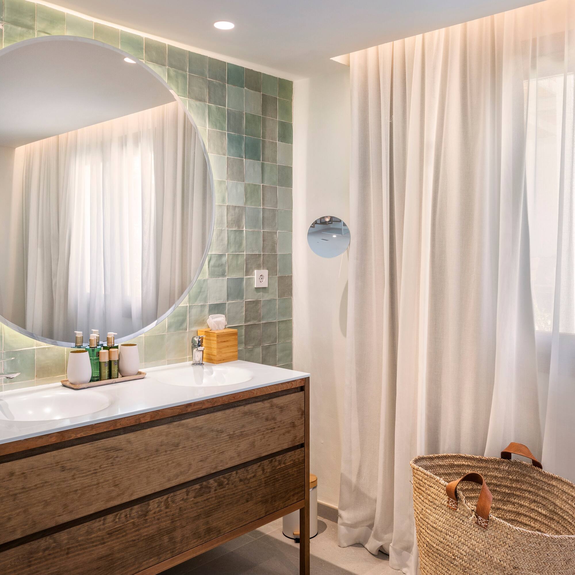 a bathroom with a round mirror and a basket