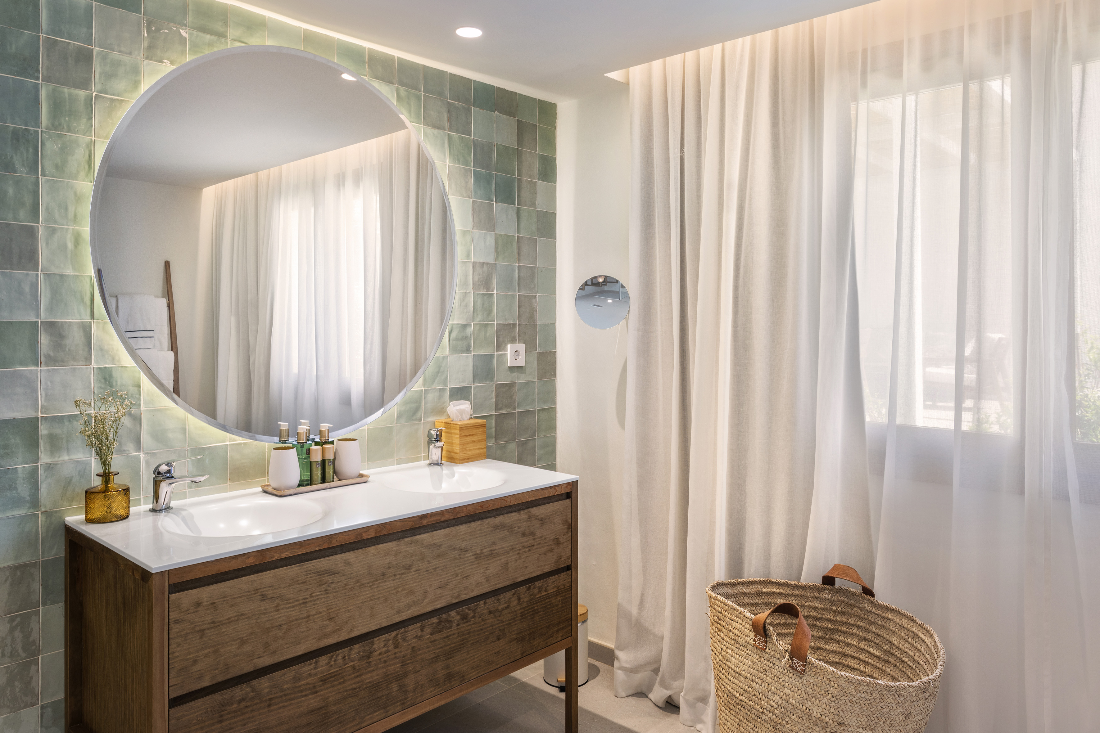a bathroom with a round mirror and a basket