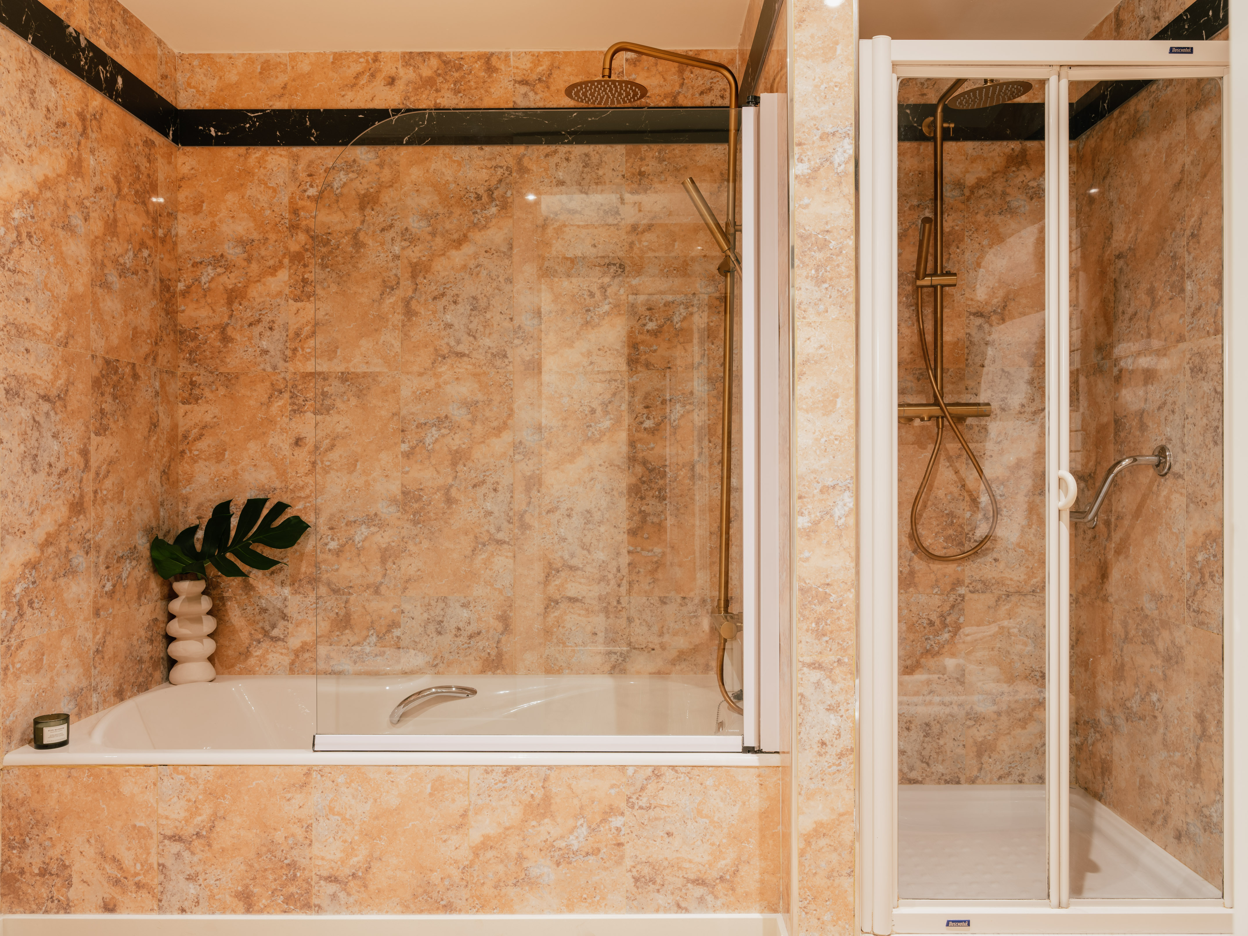 Earth-toned tiled bathroom with tub shower combo and separate walk-in shower.
