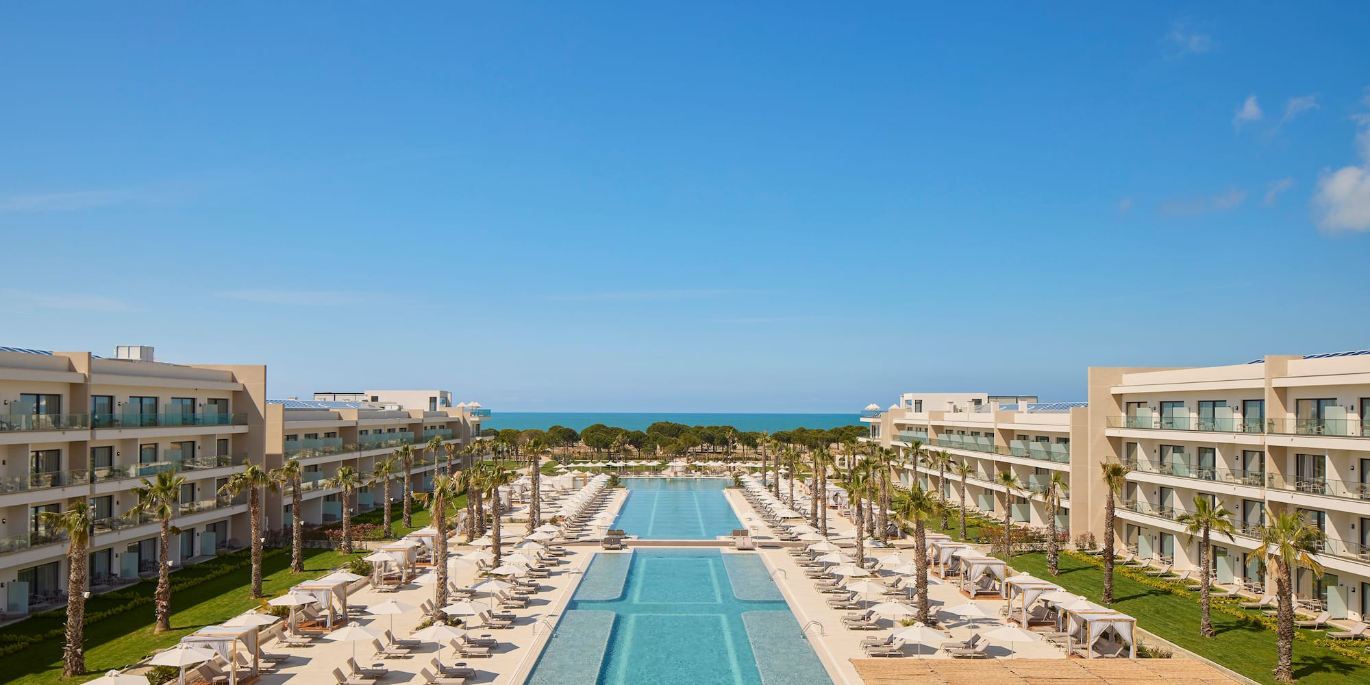 a swimming pool with chairs and trees in front of buildings