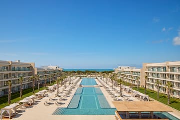 a swimming pool with chairs and trees in front of buildings