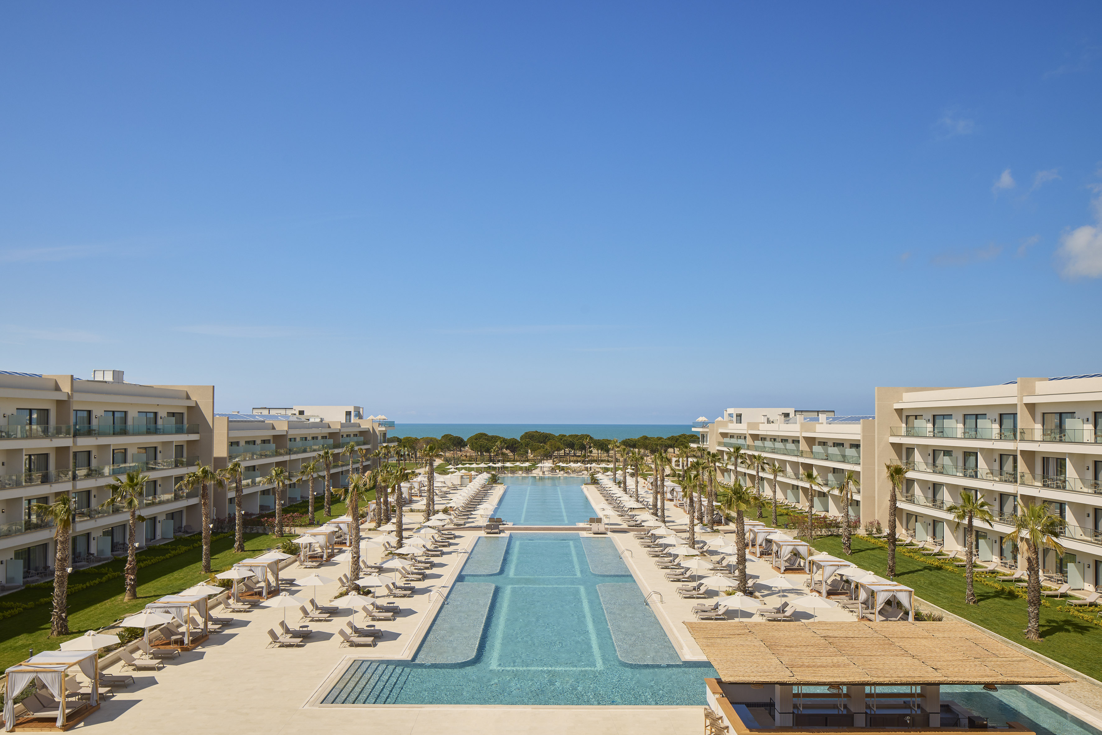 a swimming pool with chairs and trees in front of buildings