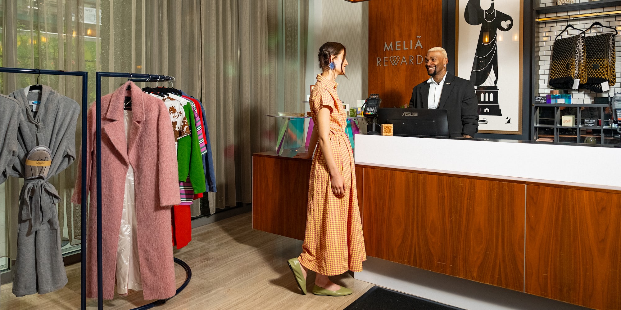 Melia Rewards hotel reception with guest, smiling staff, and fashion items on display.