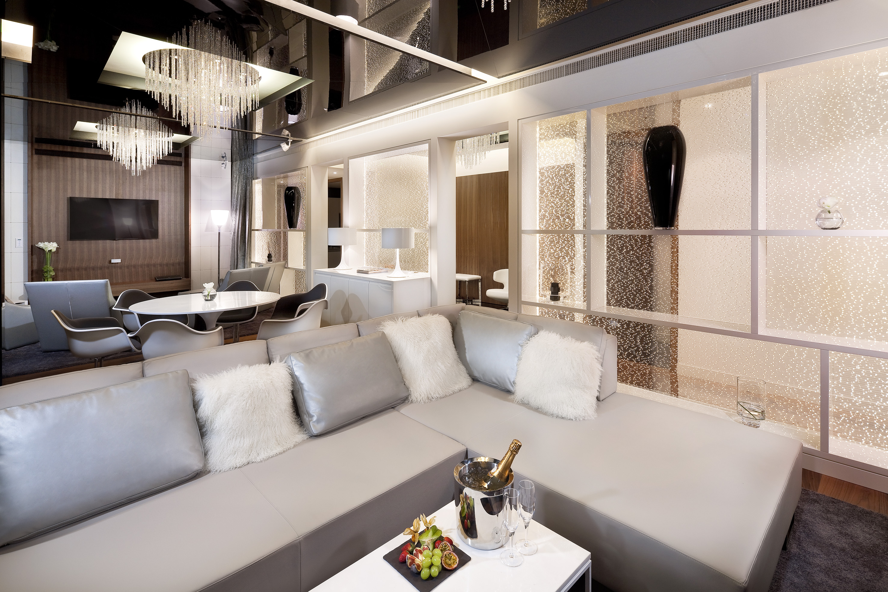 Luxury hotel suite living room with grey sectional sofa, champagne, modern design.