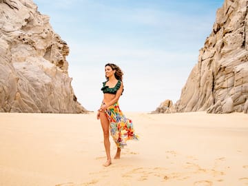 a woman in a garment and skirt walking on a beach