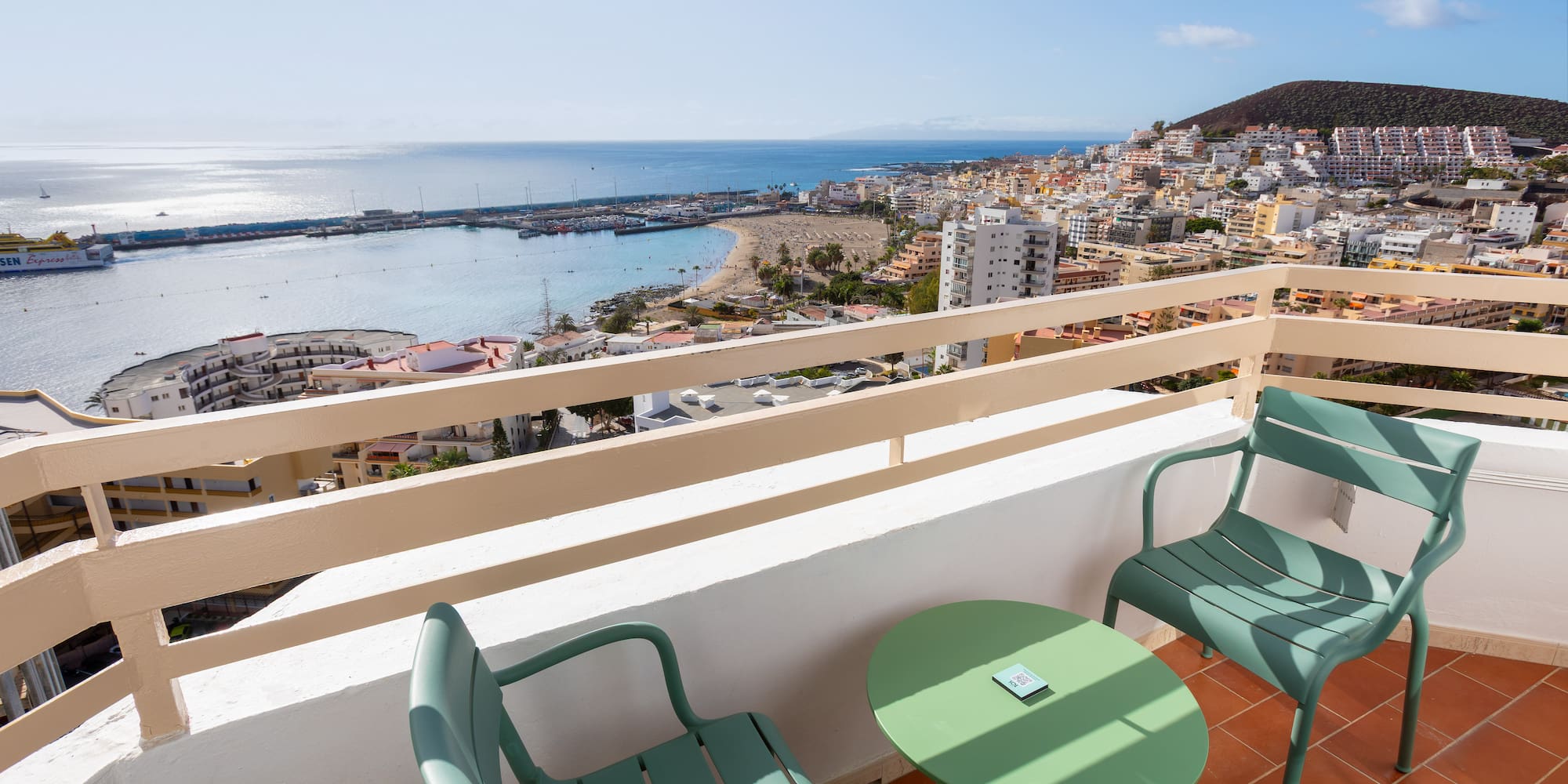 a balcony with chairs and a table overlooking a city