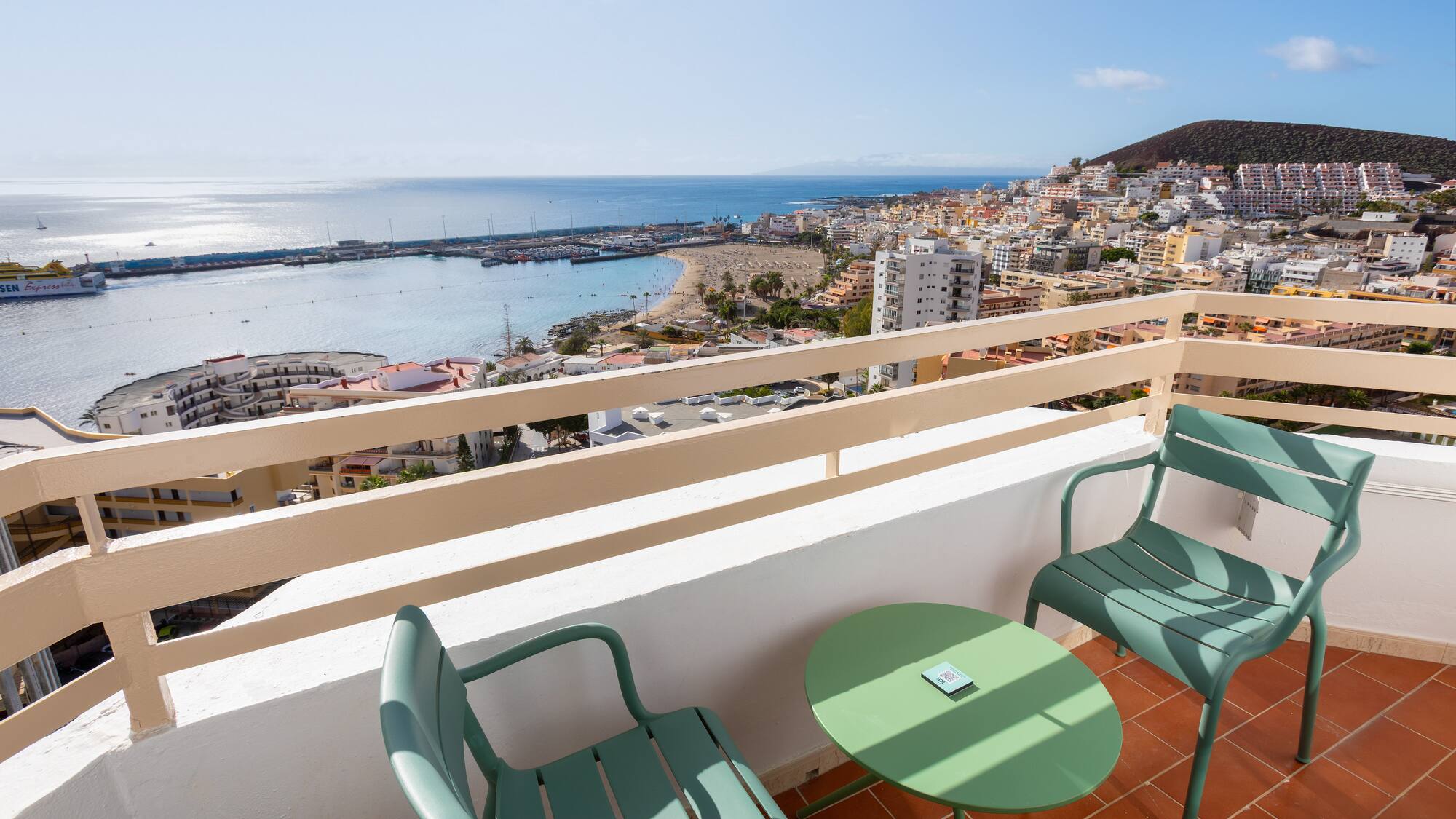 a balcony with chairs and a table overlooking a city