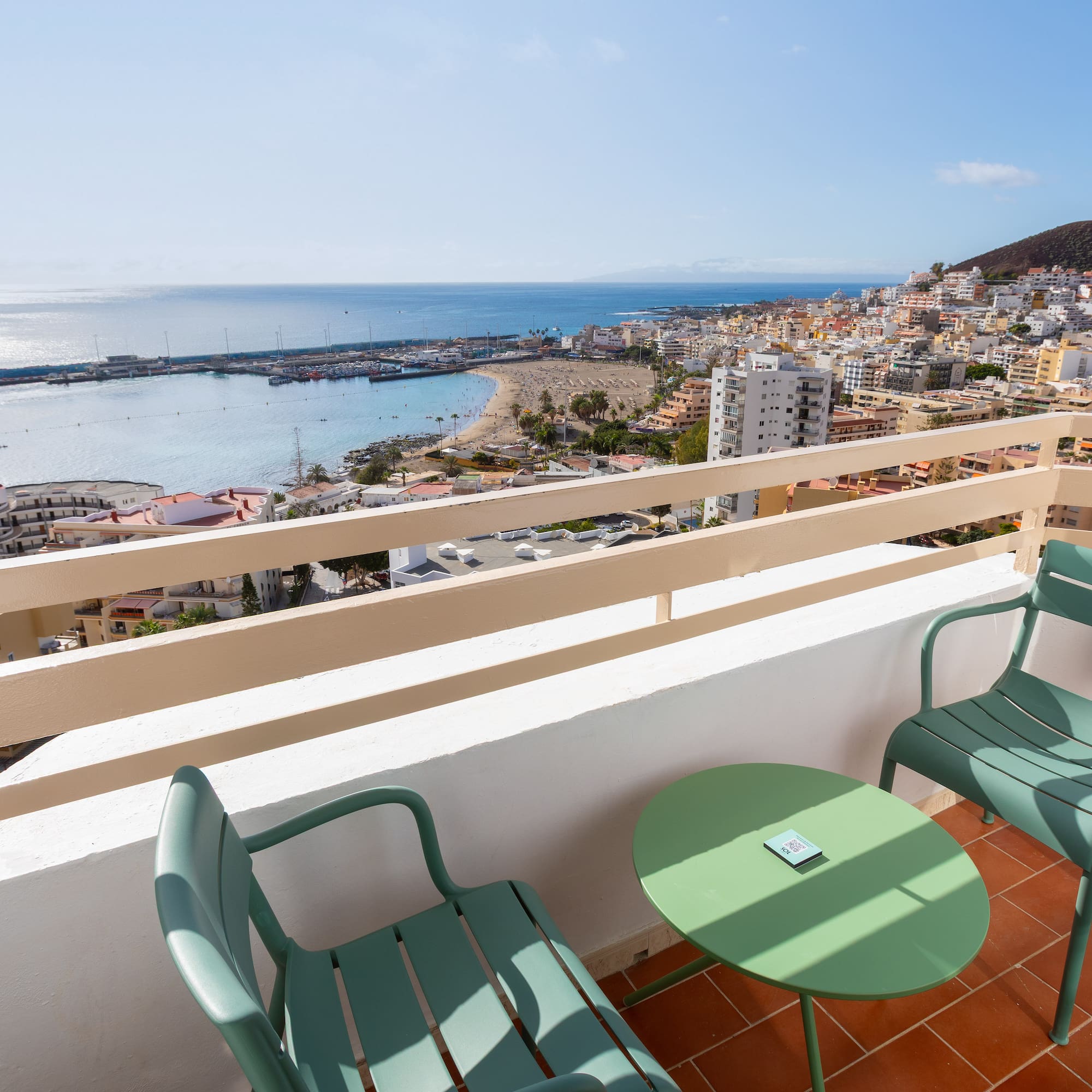 a balcony with chairs and a table overlooking a city