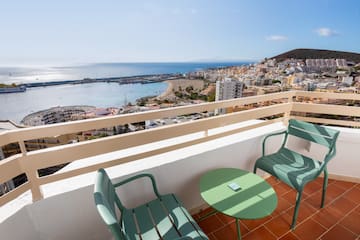 a balcony with chairs and a table overlooking a city