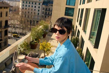 a person holding a cup of coffee on a balcony