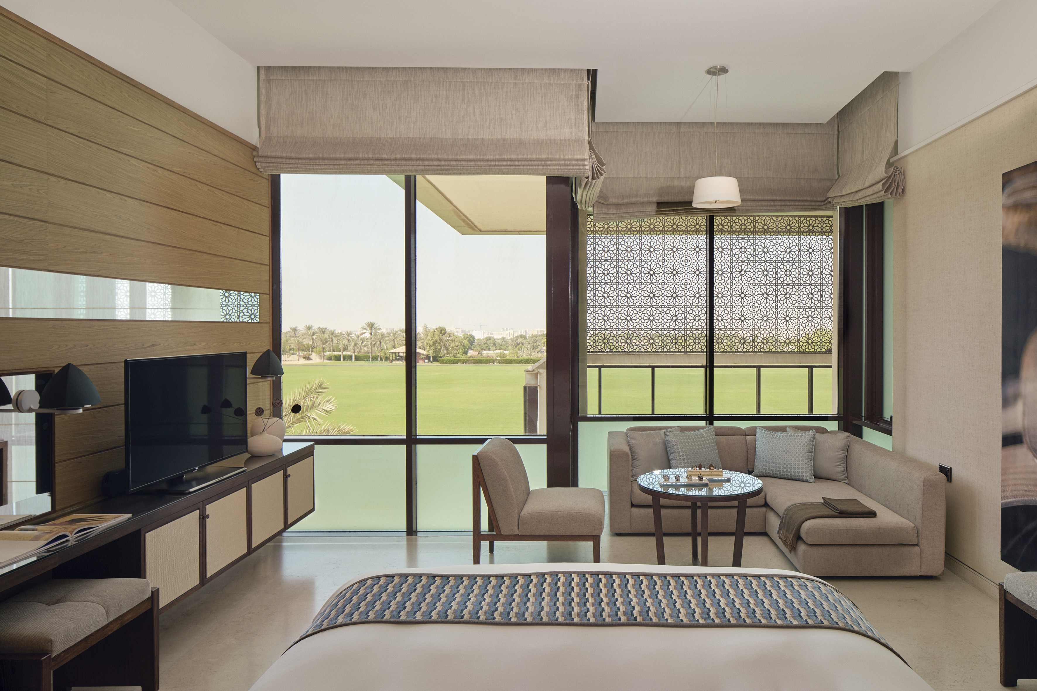 Hotel bedroom with expansive golf course view, modern decor, and living area.