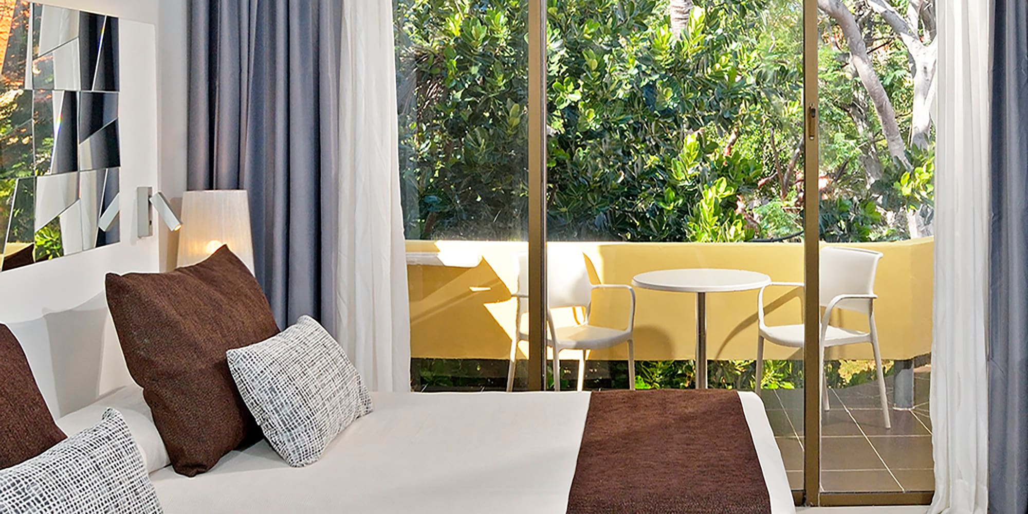 a bed with brown pillows and a glass door