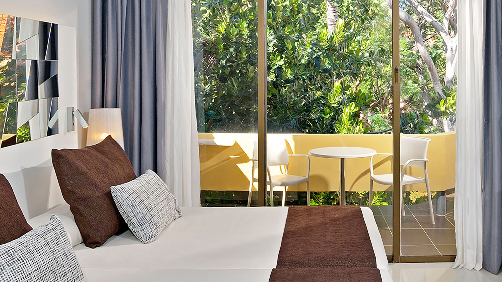 a bed with brown pillows and a glass door