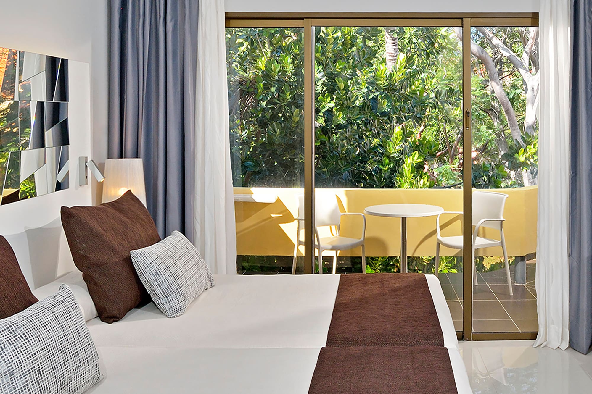 a bed with brown pillows and a glass door