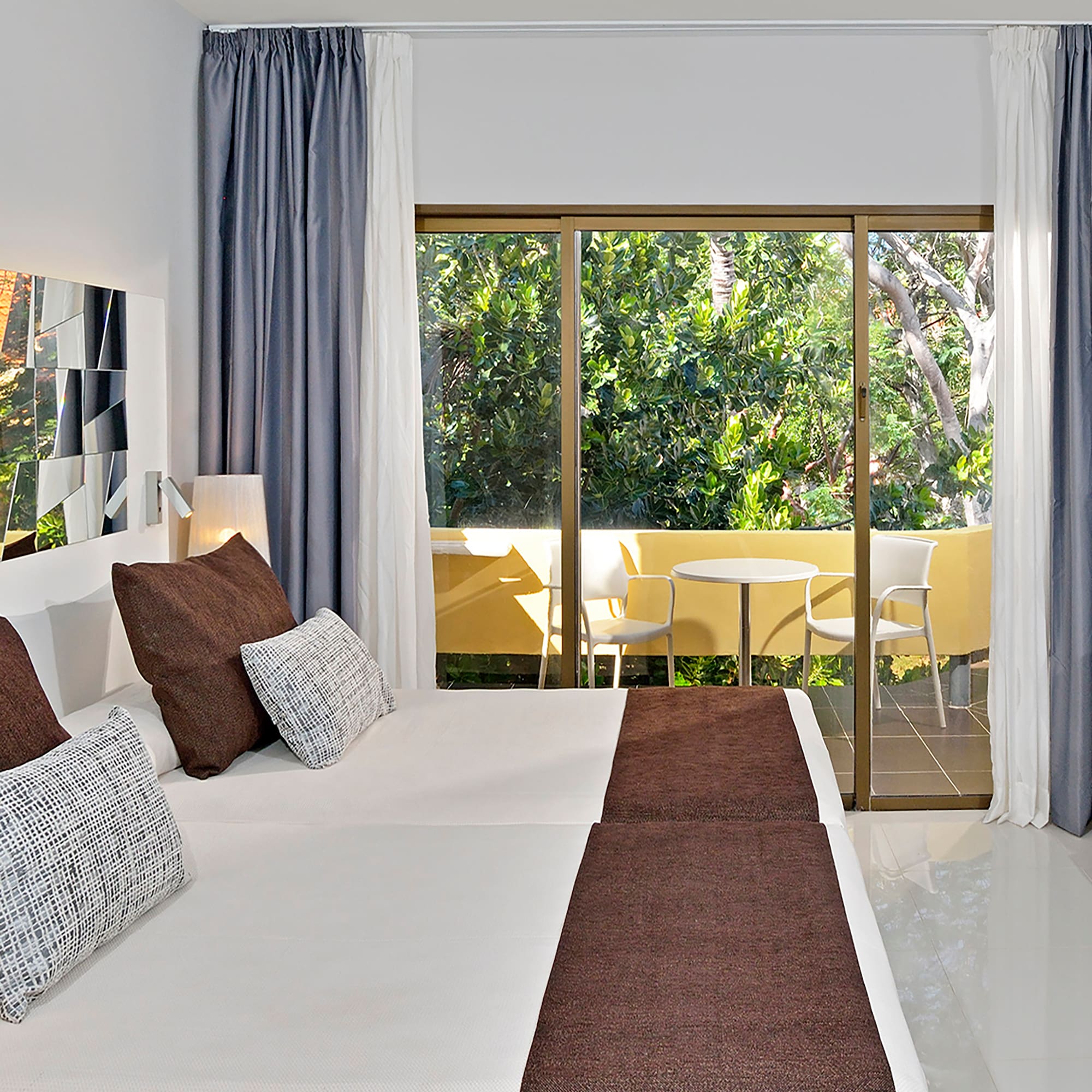 a bed with brown pillows and a glass door