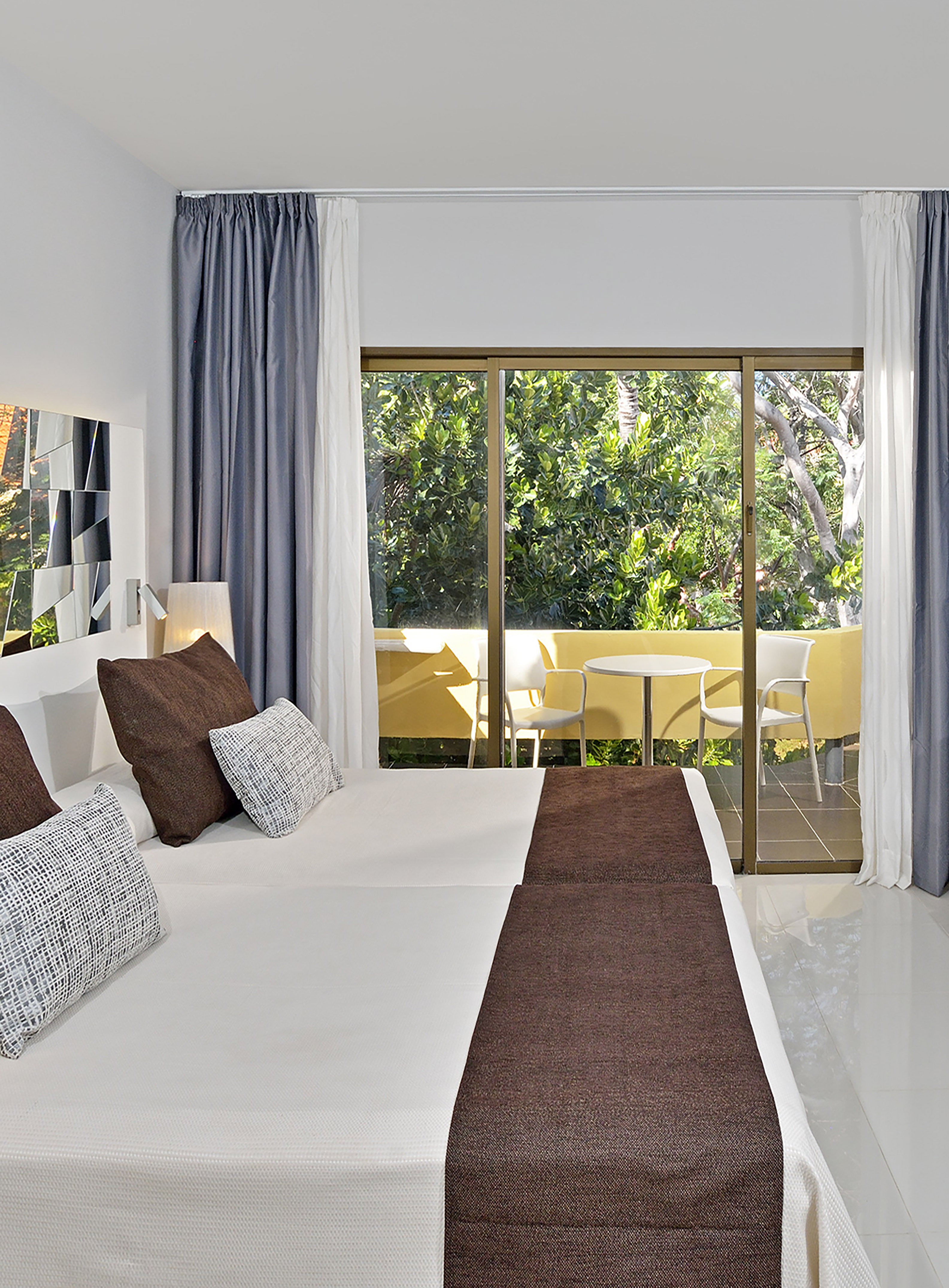 a bed with brown pillows and a glass door