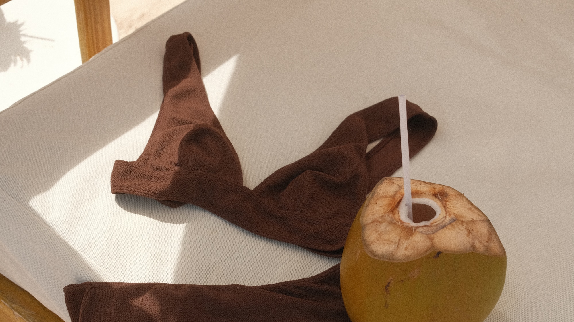 a coconut with a straw and a brown garment on a white surface