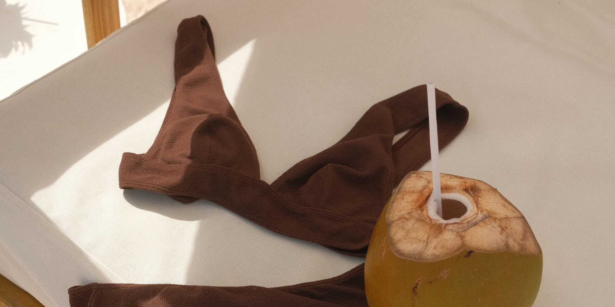 a coconut with a straw and a brown garment on a white surface
