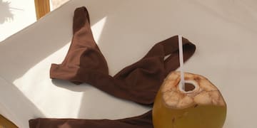 a coconut with a straw and a brown garment on a white surface