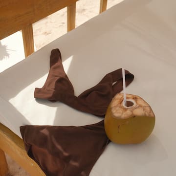 a coconut with a straw and a brown garment on a white surface