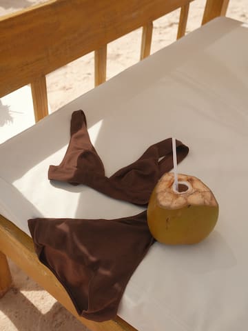 a coconut with a straw and a brown garment on a white surface