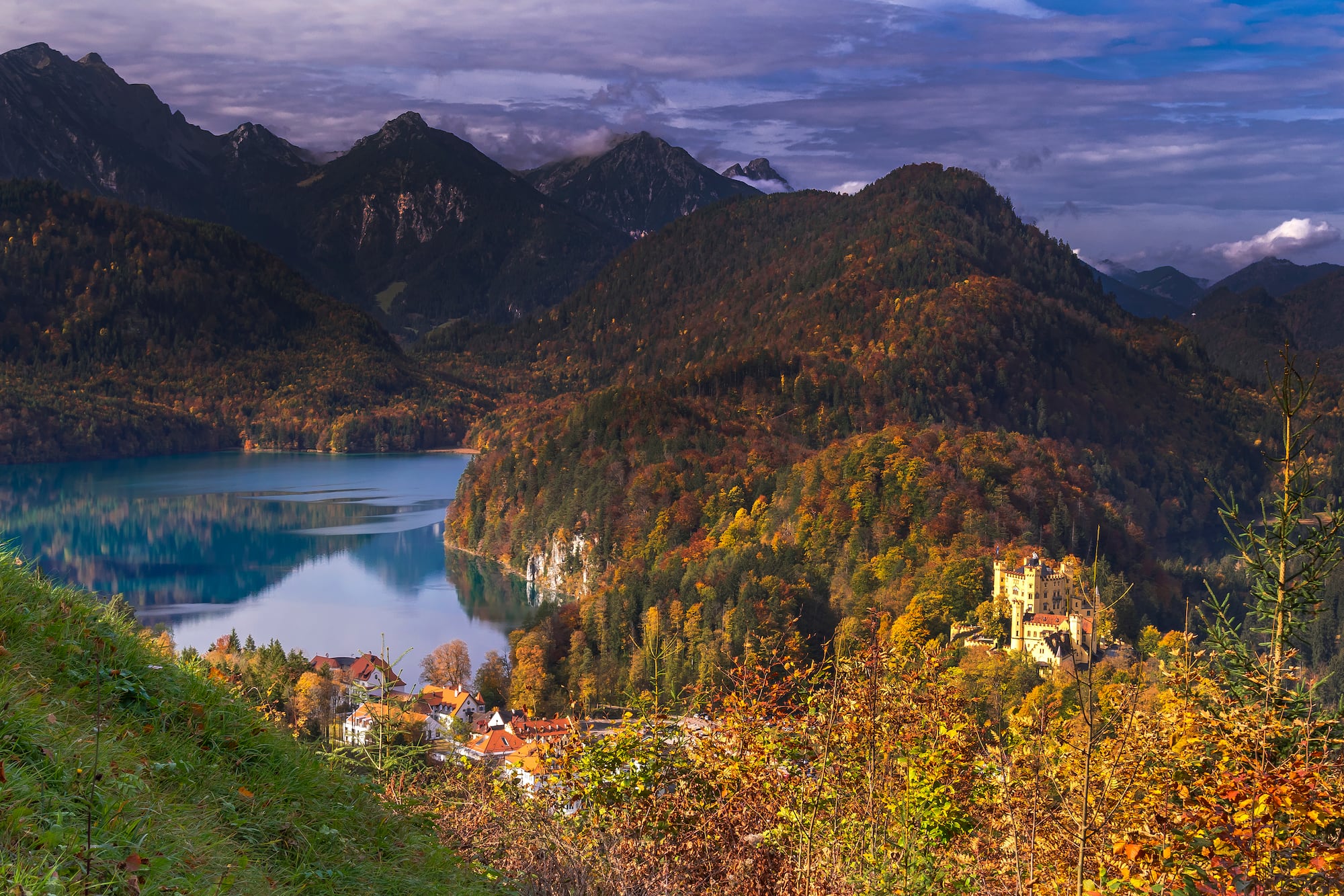 Castillo Hohenschwangau, lago Alpsee, montañas y bosque otoñal.