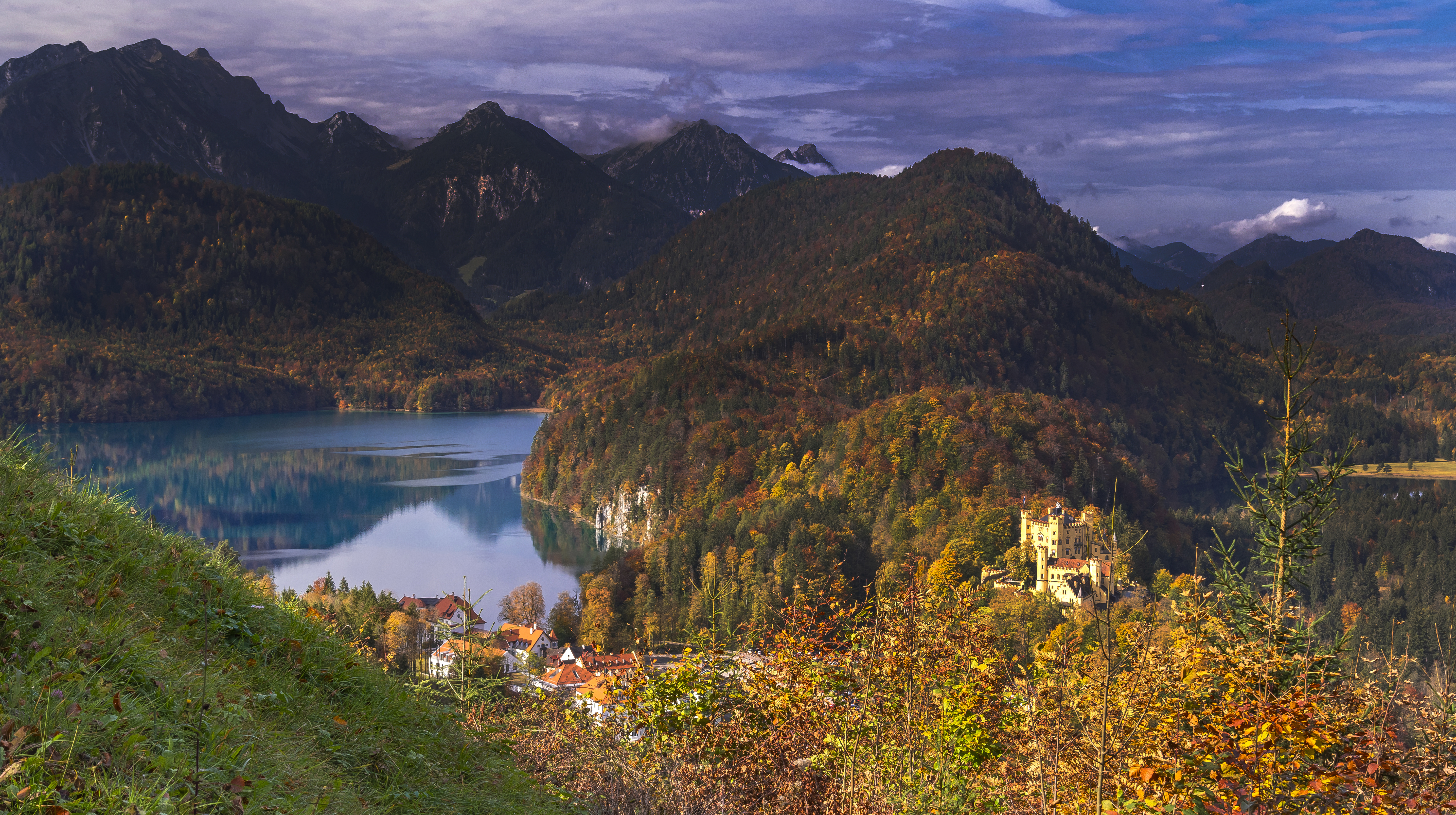 Castillo Hohenschwangau, lago Alpsee, montañas y bosque otoñal.