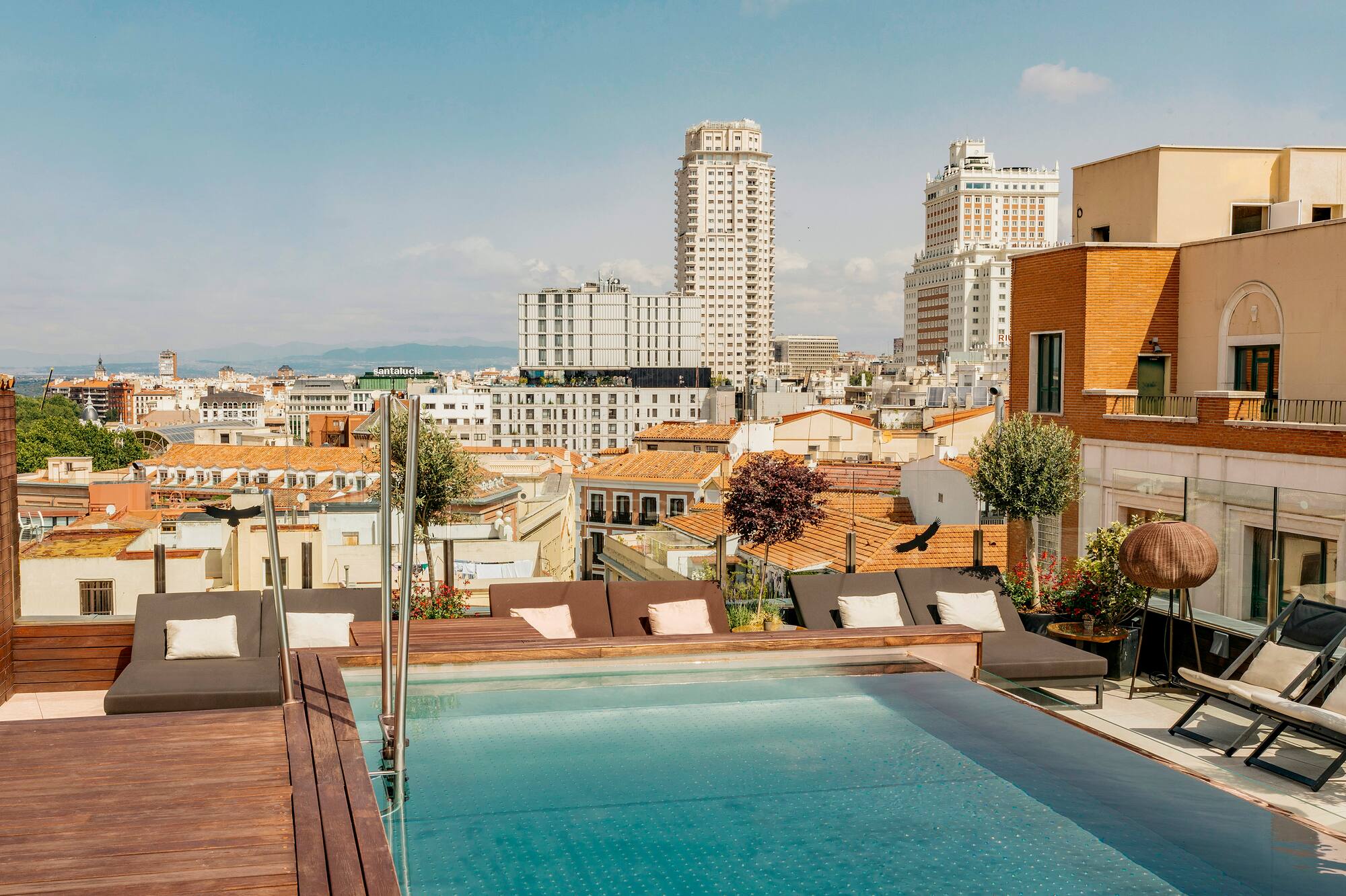 Rooftop infinity pool with Madrid city skyline view and lounge chairs.