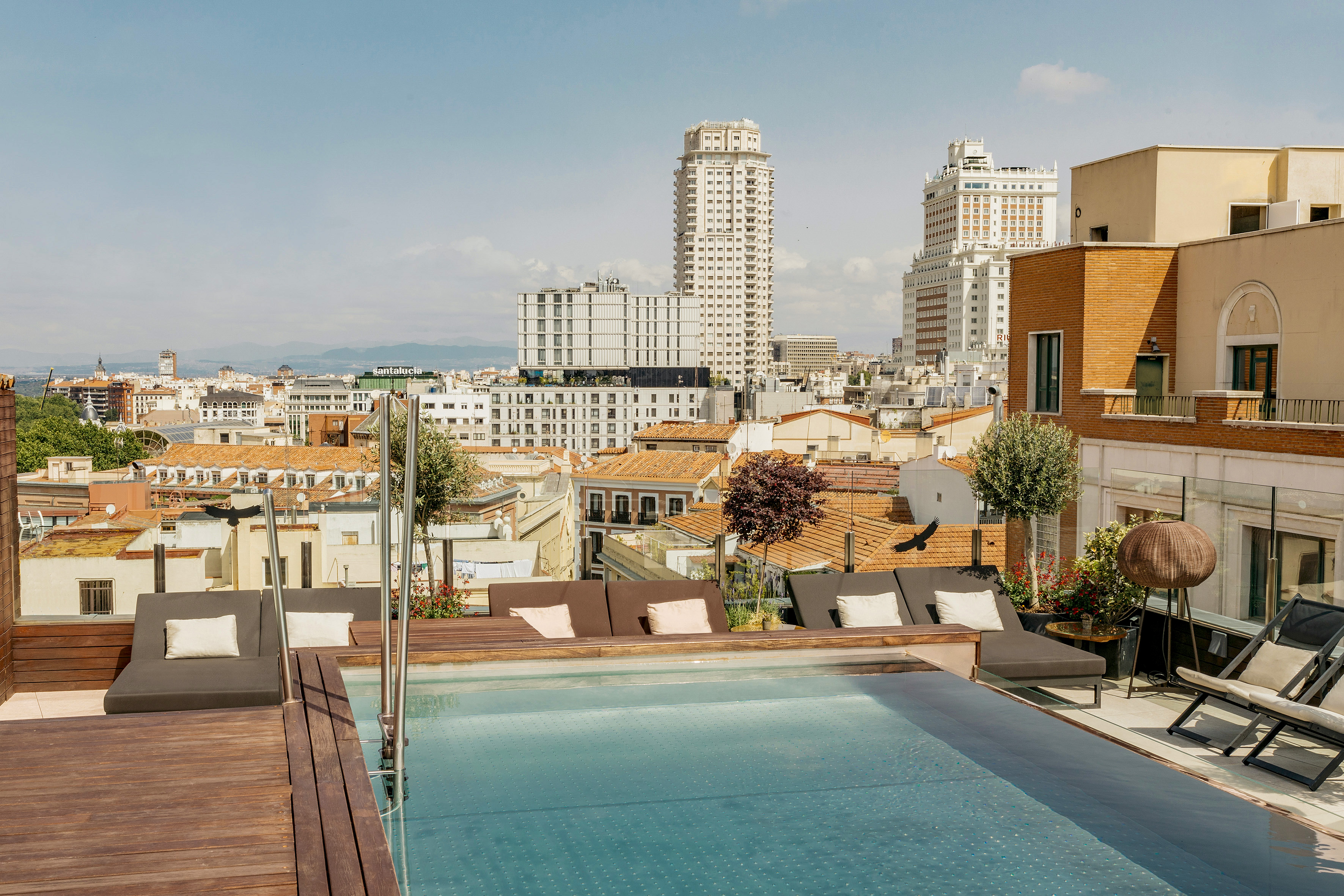 Rooftop infinity pool with Madrid city skyline view and lounge chairs.
