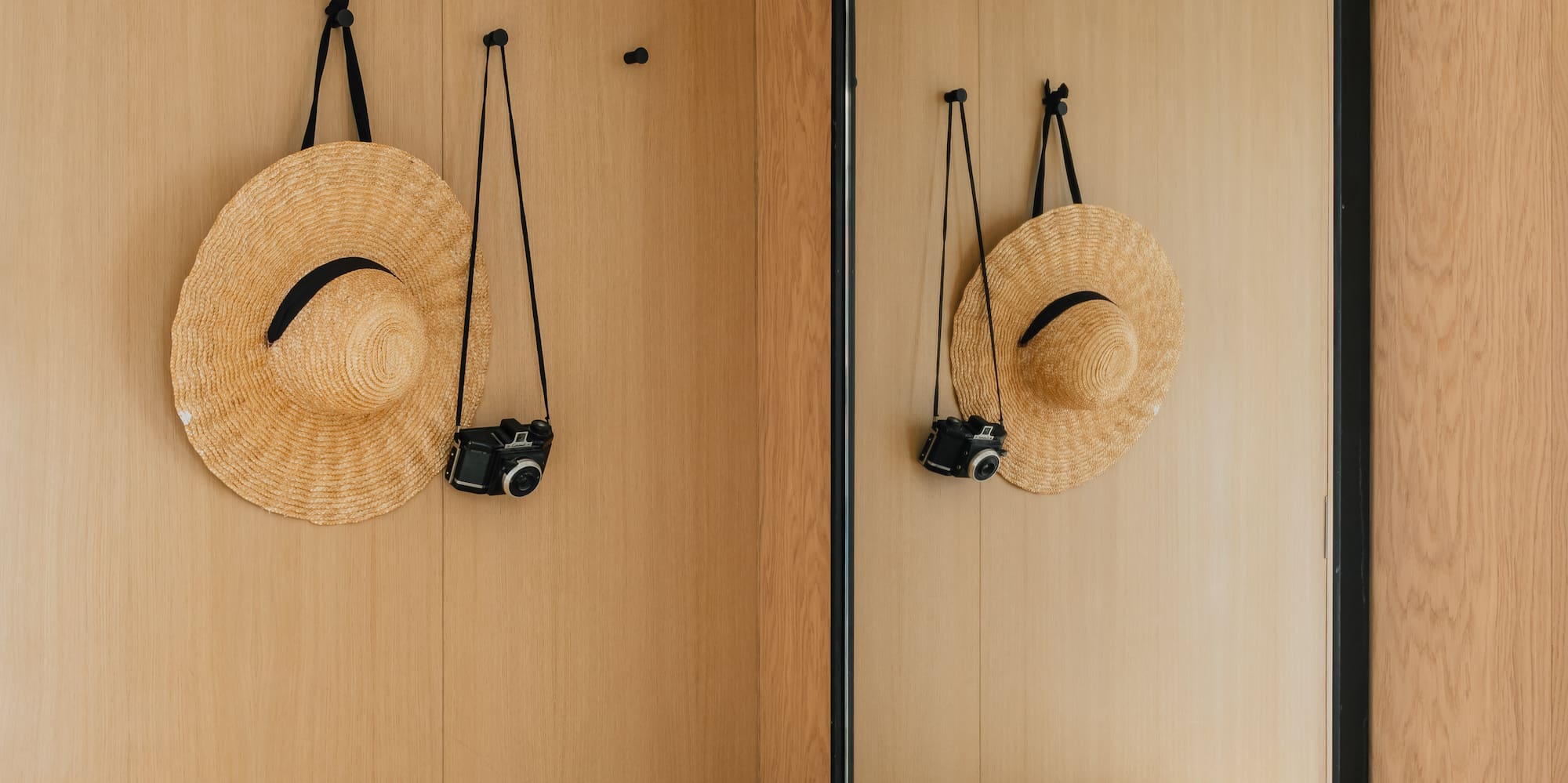 Modern entryway with wooden walls, straw hat, vintage camera, bench, and large mirror.