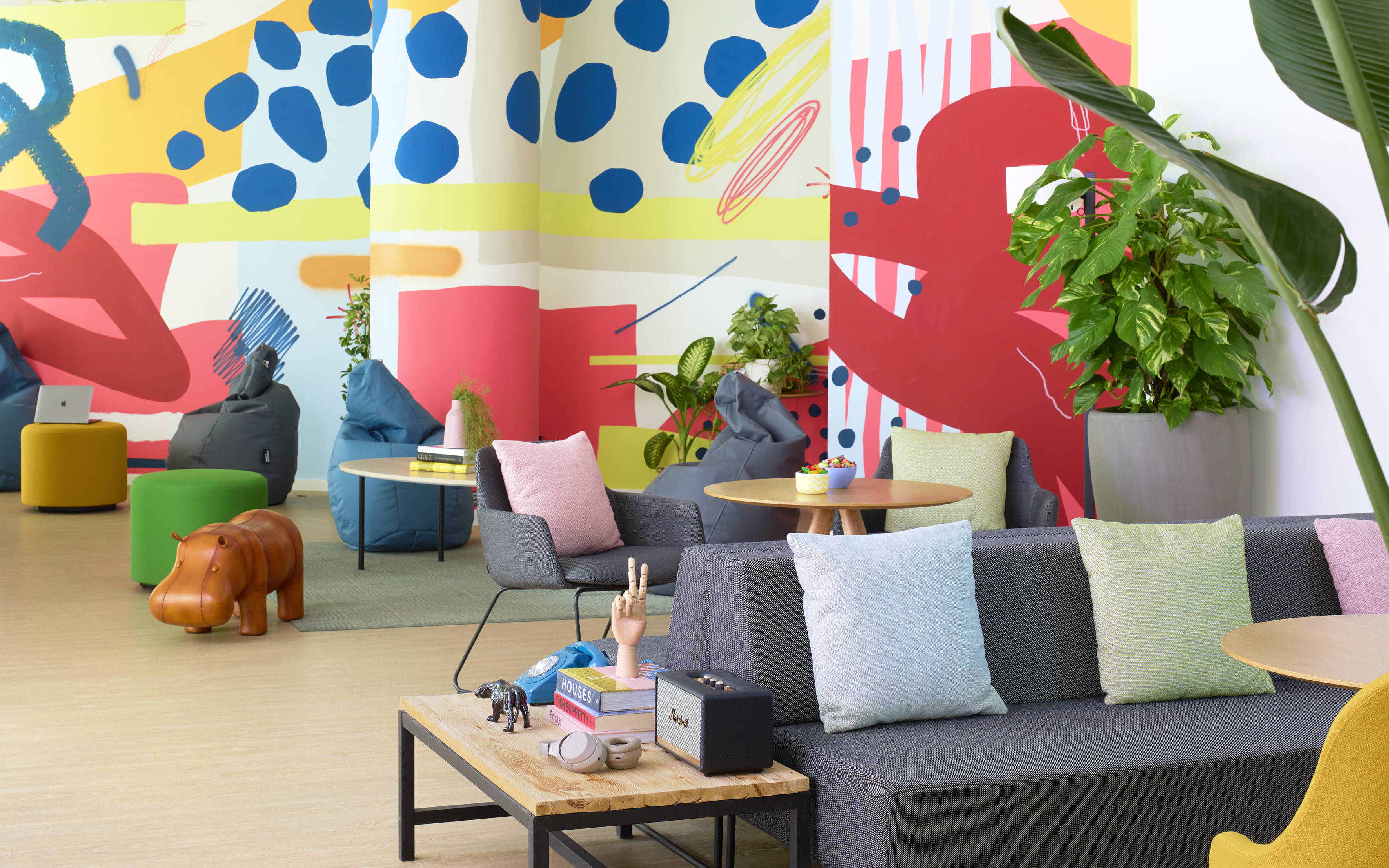 Colorful coworking lounge with abstract murals and various seating.