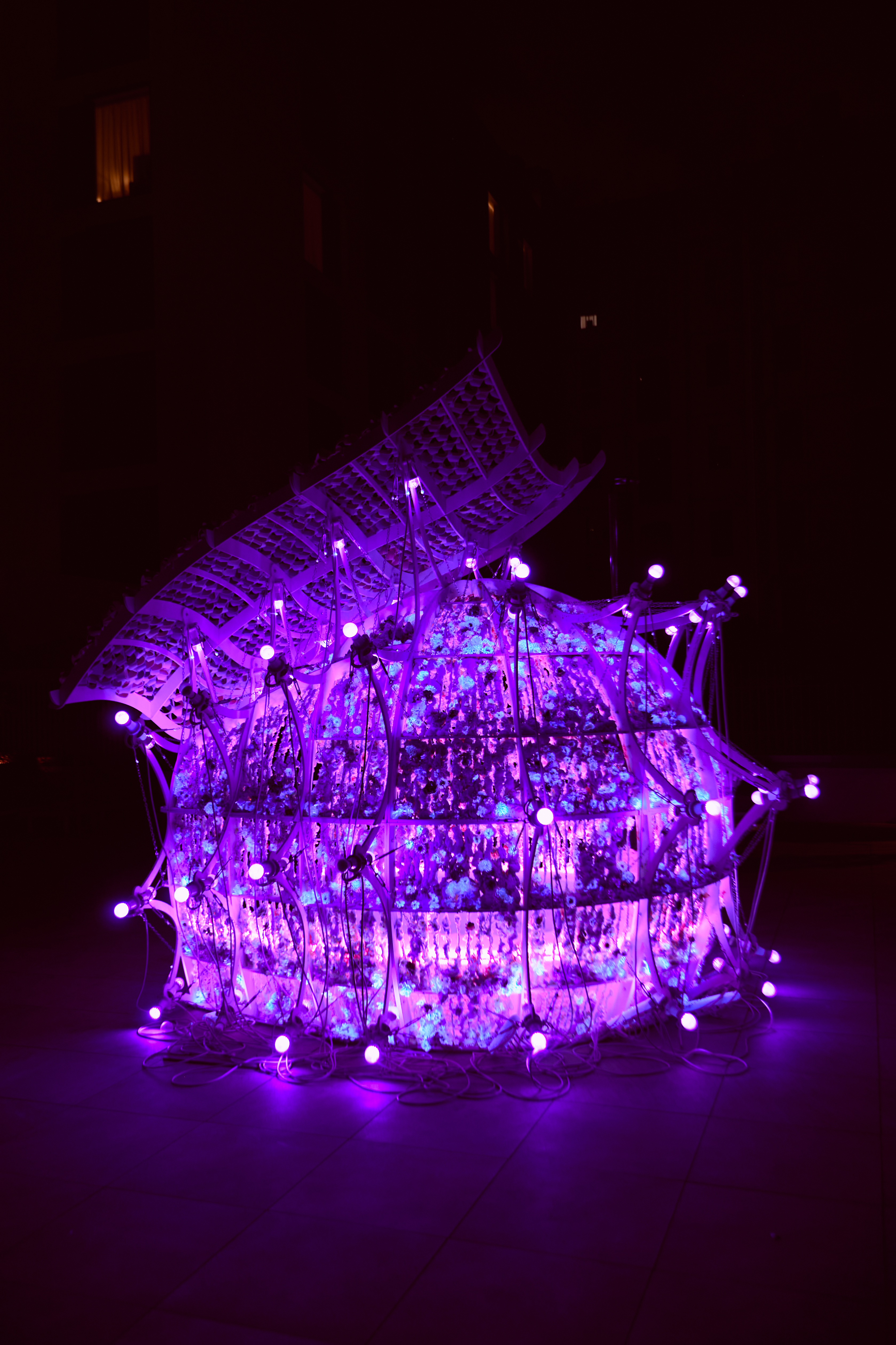 Purple glowing vertical garden structure with violet lights at night.