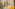 Modern interior with yellow armchair, plant, and gallery wall of travel city art.