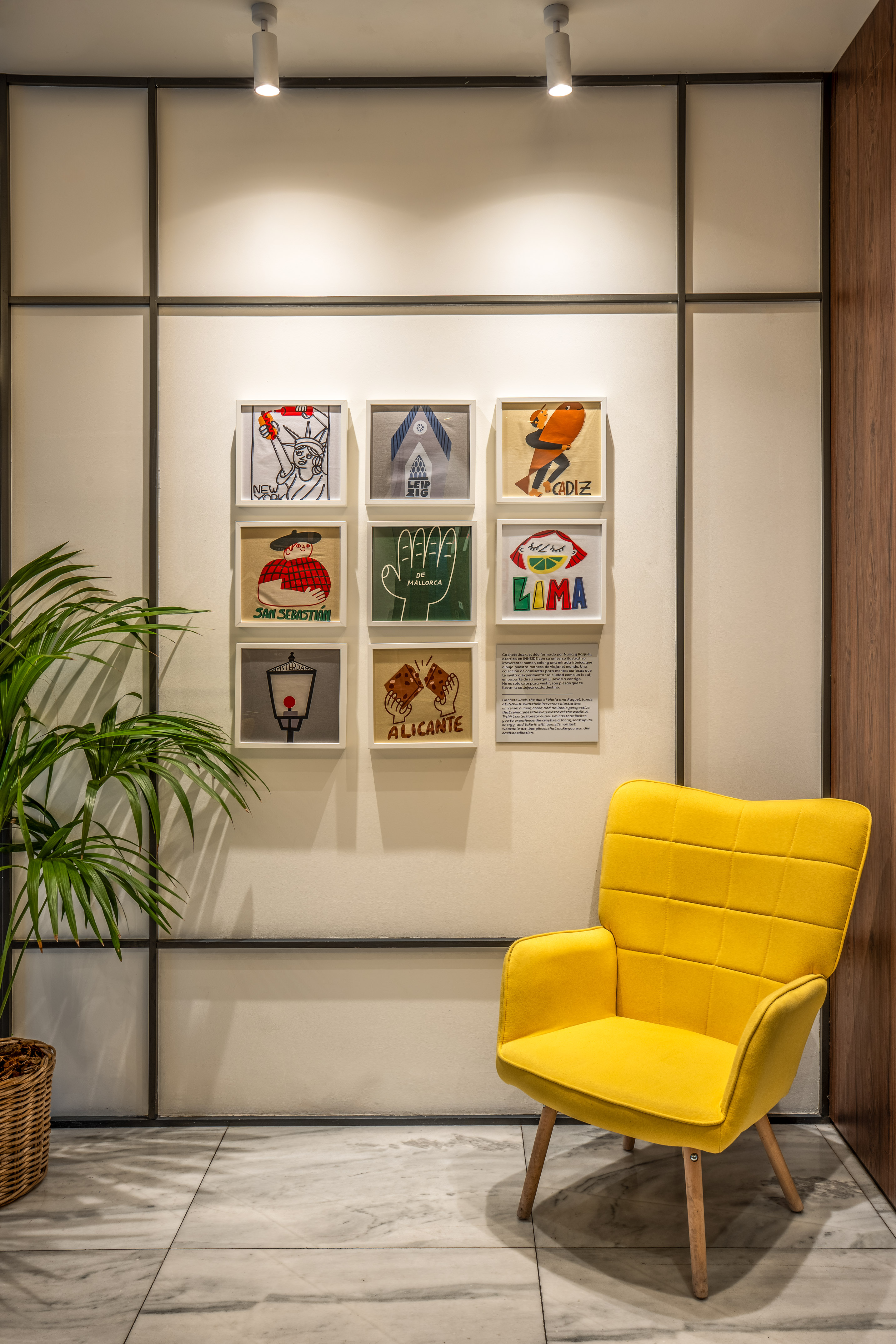 Modern hotel lounge with vibrant yellow chair and framed illustrative travel art.