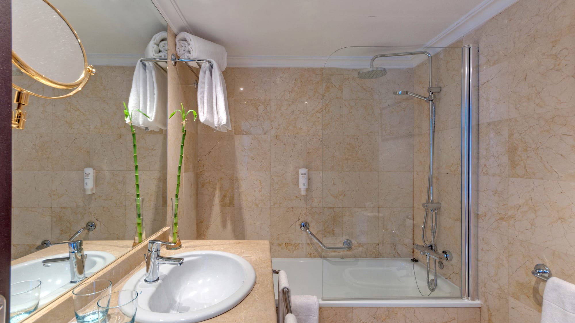 Modern hotel bathroom with marble vanity, sink, shower, bathtub, and towels.