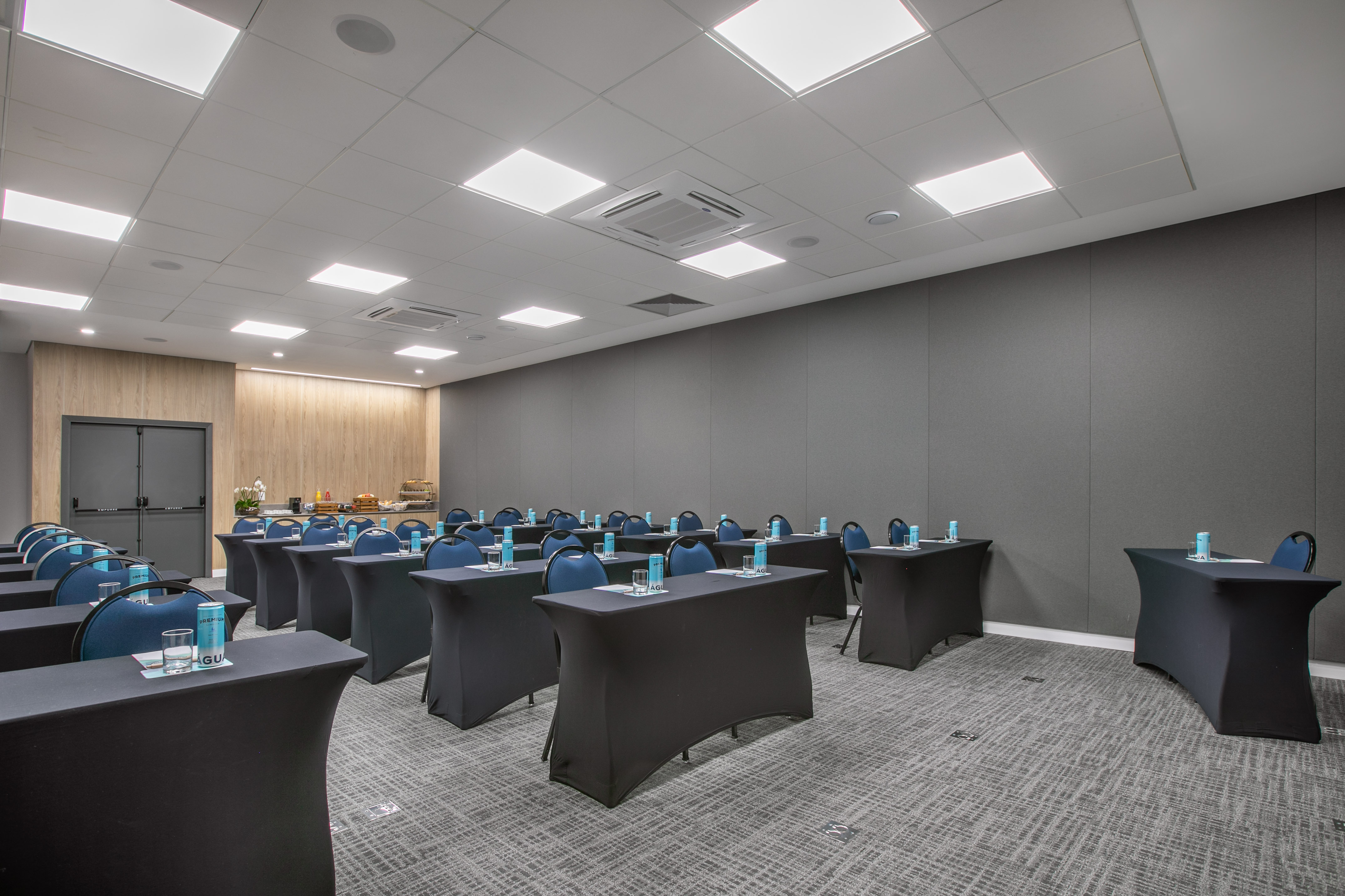 Professional meeting room with black tables, blue chairs, and refreshments.