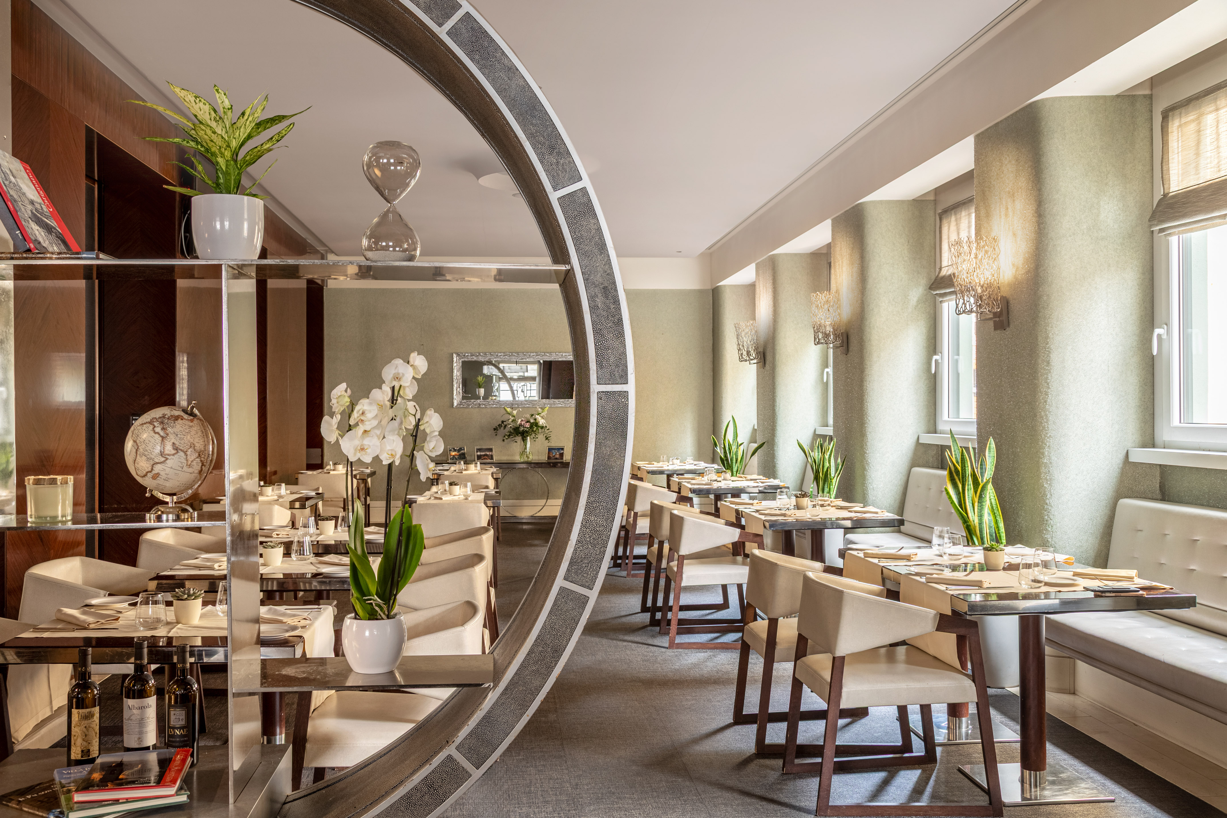Elegant modern restaurant dining room with set tables and green plants.