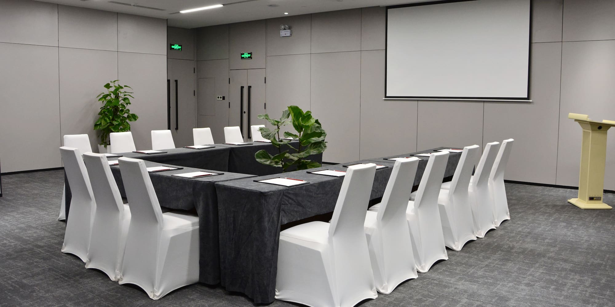a long table with chairs and a projector screen