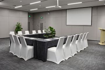 a long table with chairs and a projector screen