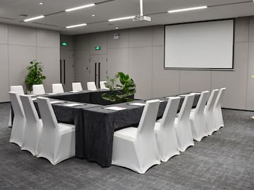 a long table with chairs and a projector screen