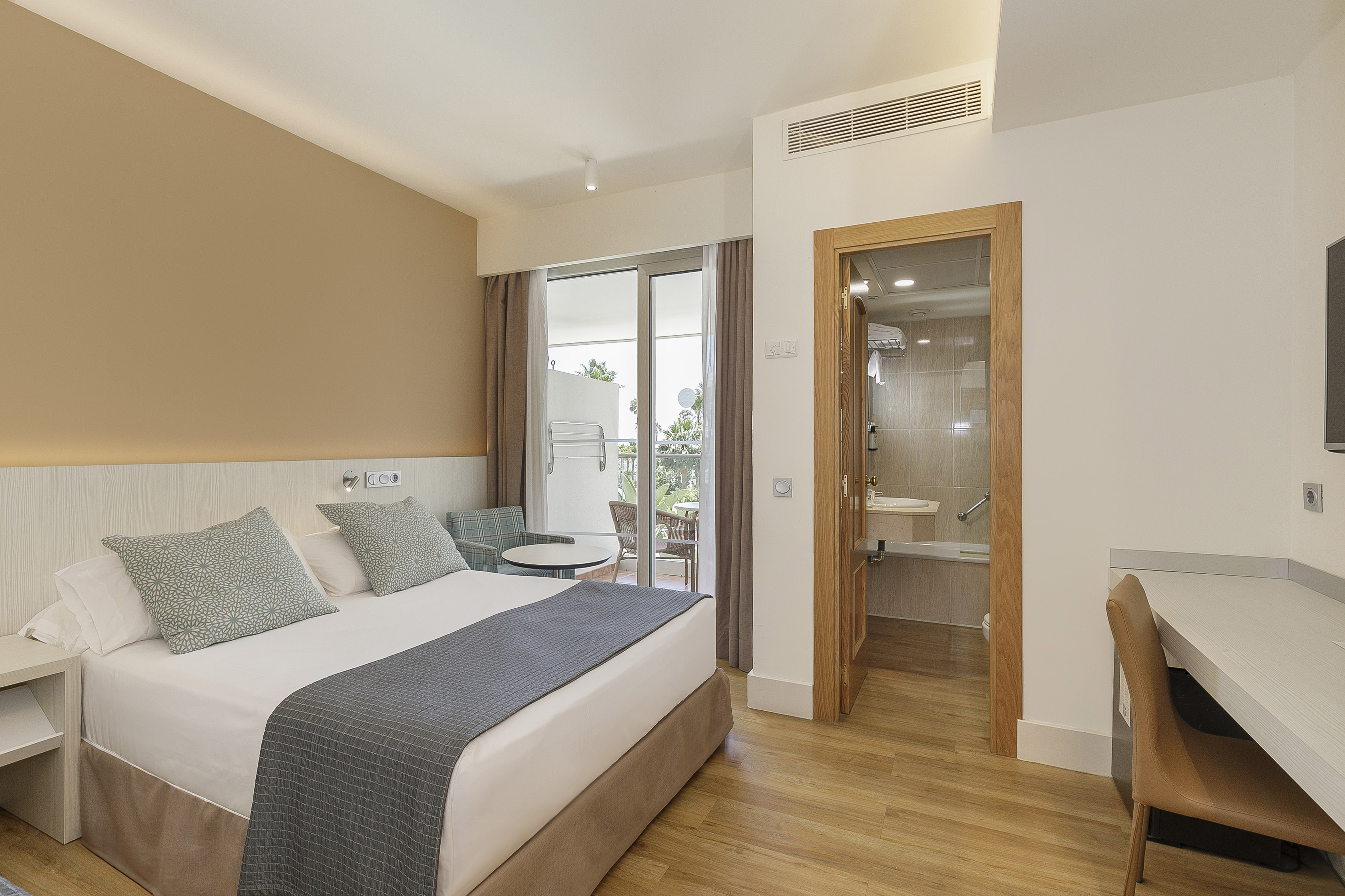 Modern hotel room with bed, balcony access, and en-suite bathroom.