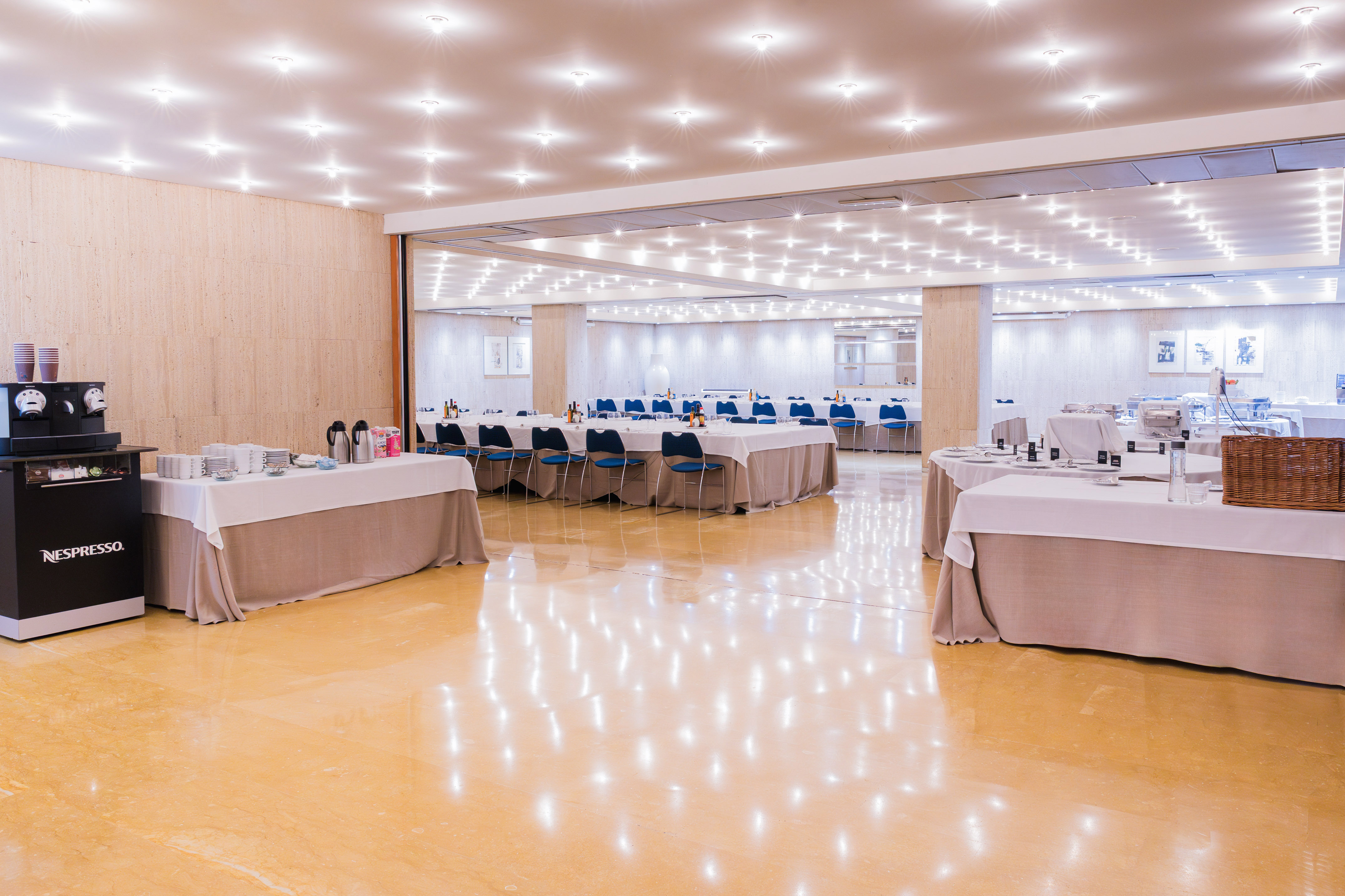 Nespresso coffee station, buffet, and dining tables in a bright conference room.