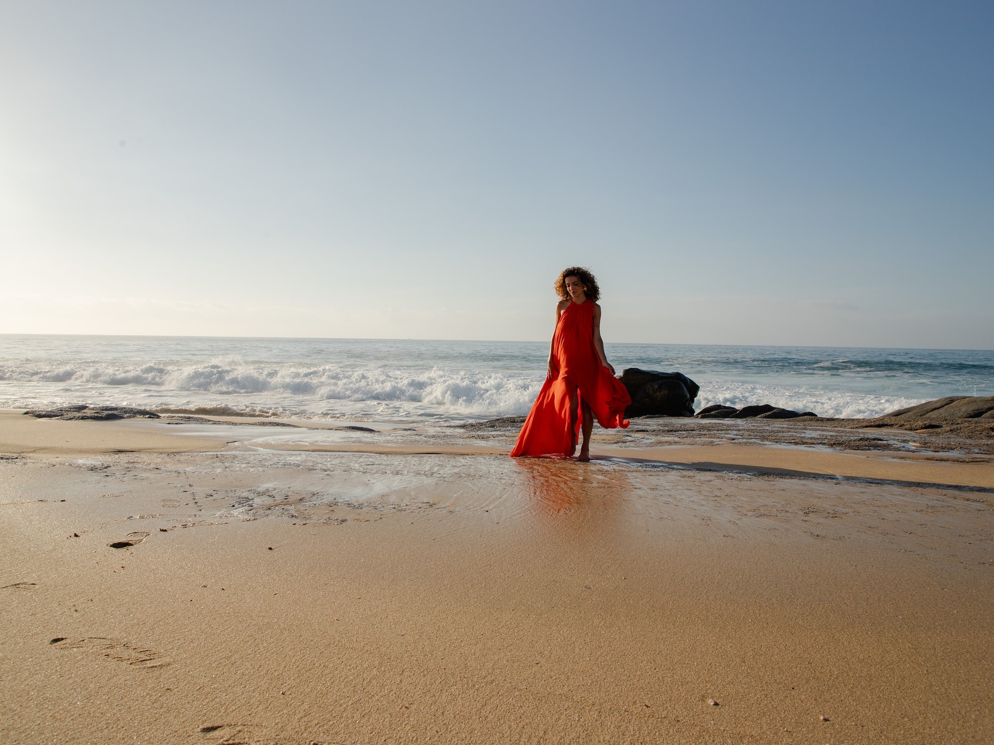 a woman in a red dress on a beach