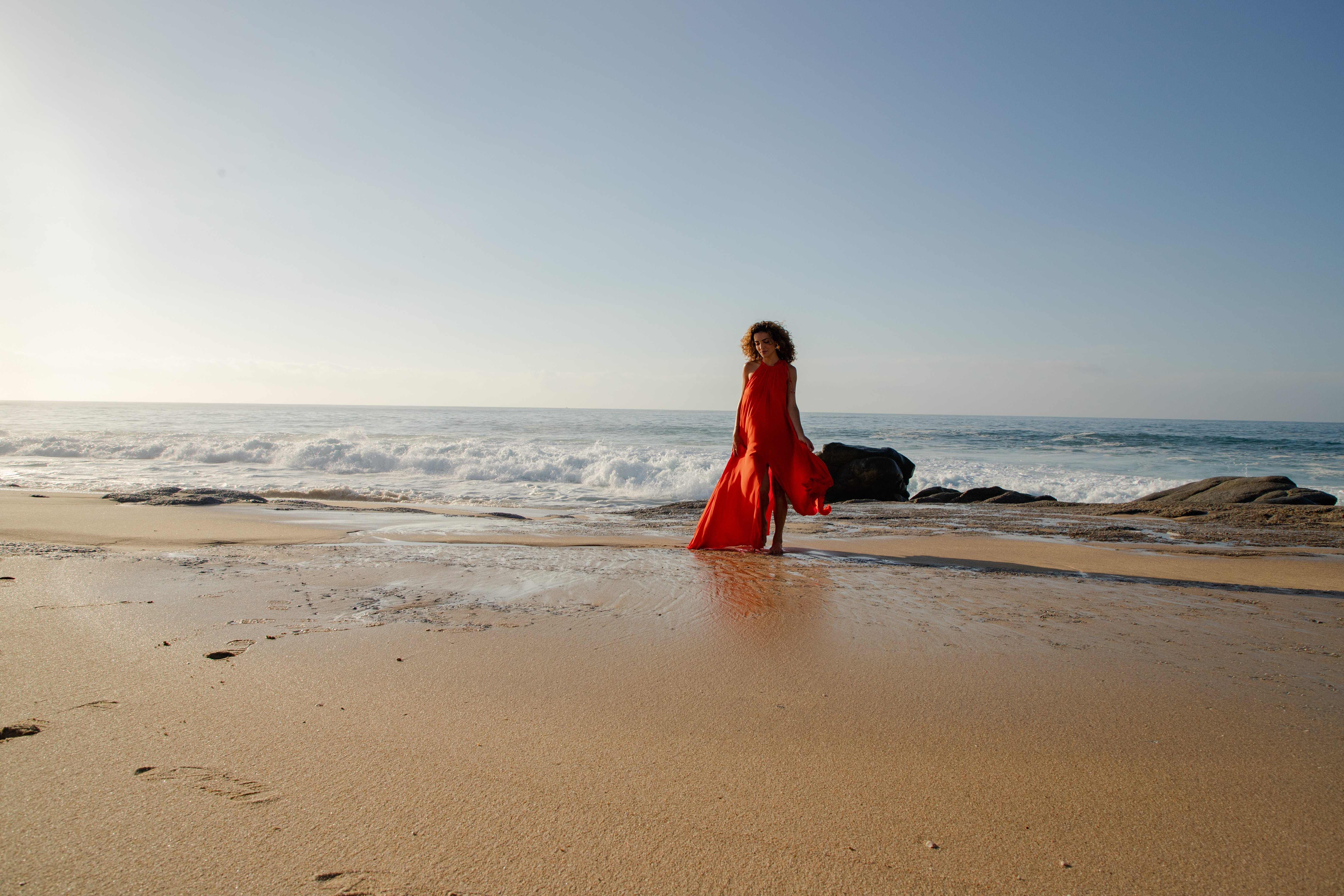 a woman in a red dress on a beach